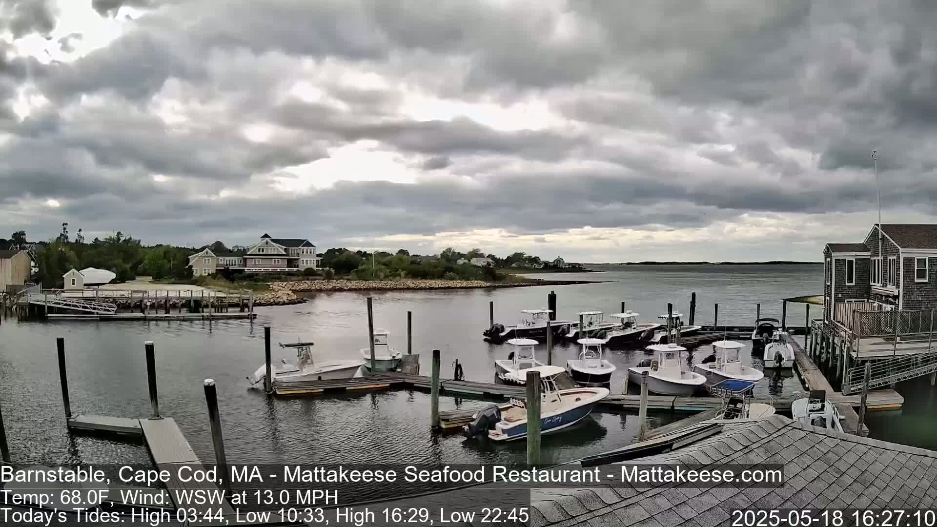 A mostly cloudy day shows a harbor with numerous boats docked at piers near houses and buildings.