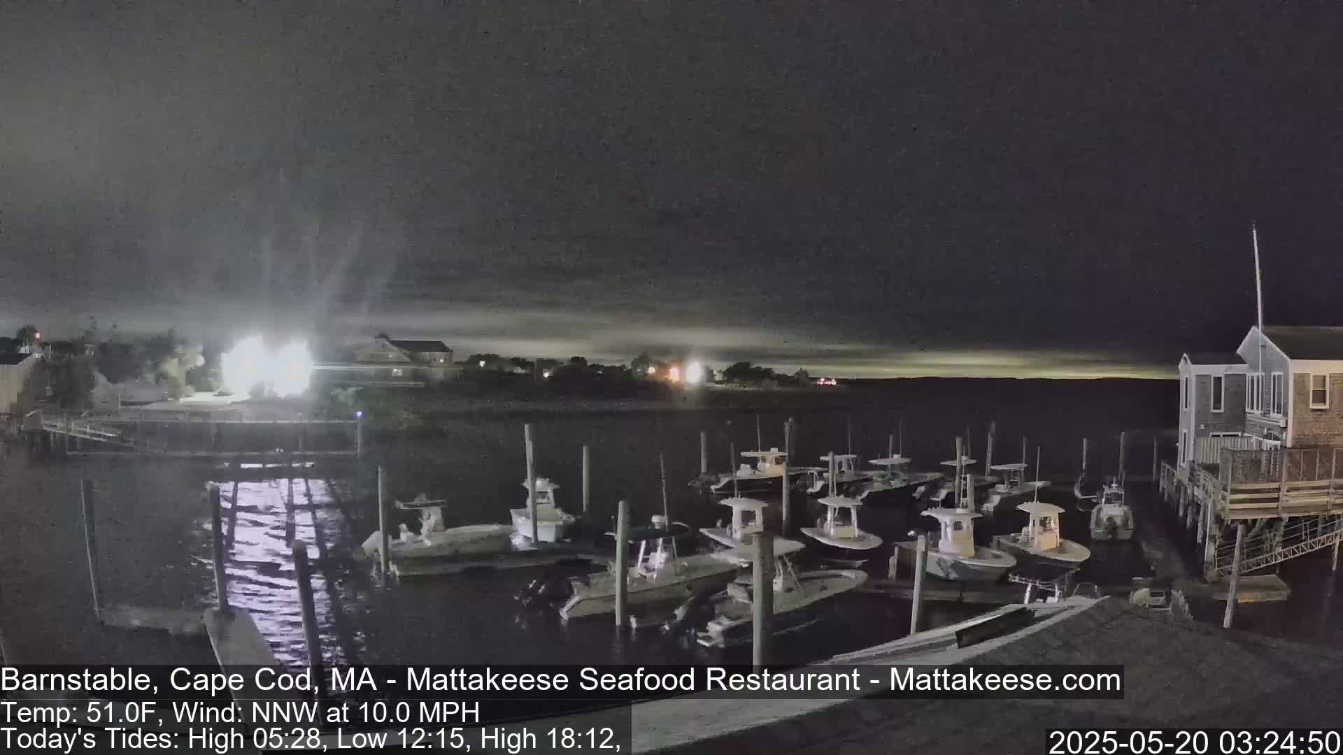 A nighttime view of a harbor with numerous small boats docked, under a mostly clear sky.