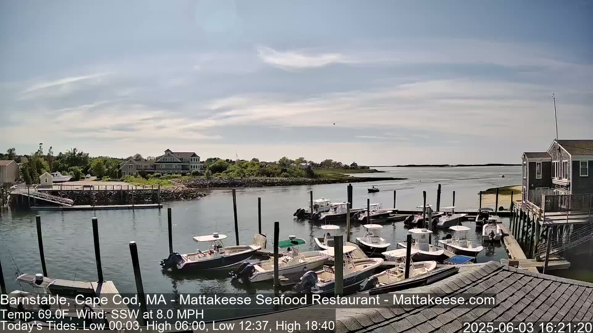 Many motorboats are docked at a marina on a partly cloudy day.
