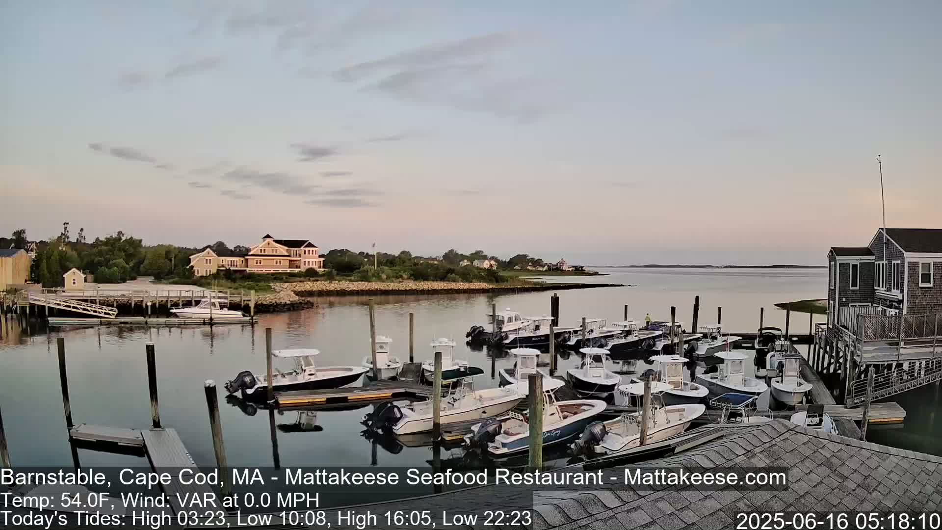 Many motorboats are docked at a calm harbor under a twilight sky.
