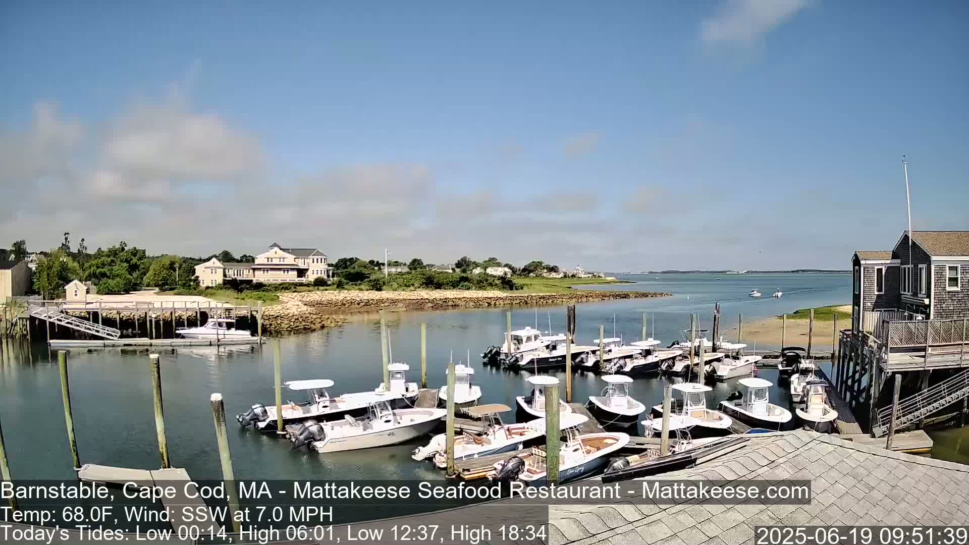 A sunny day shows a calm harbor with numerous boats docked at a waterfront building.