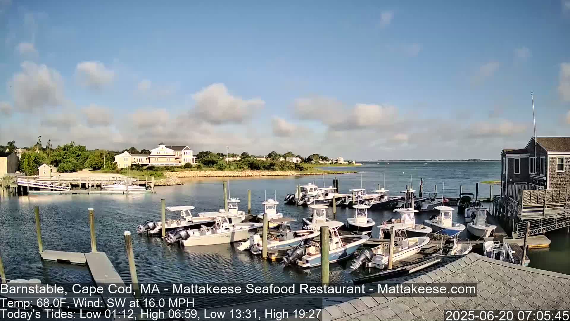 A calm harbor with numerous boats docked at a pier, under a partly cloudy sky.