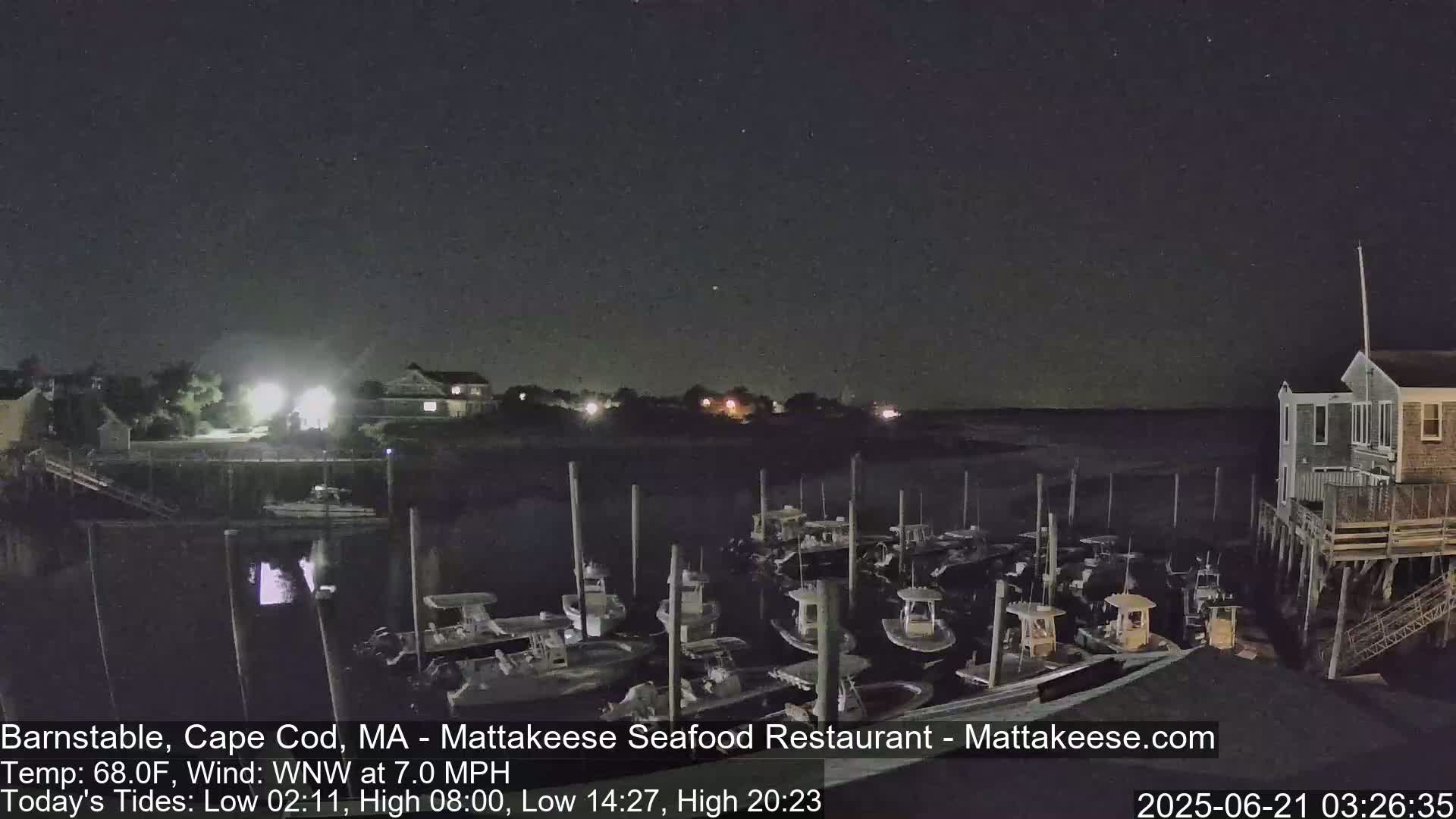 A nighttime view of a harbor filled with docked boats under a clear, dark sky.