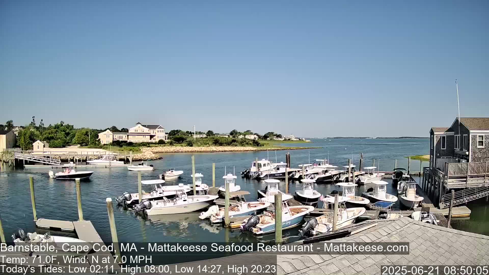 Many motorboats are docked at a marina on a sunny day with a light north wind.