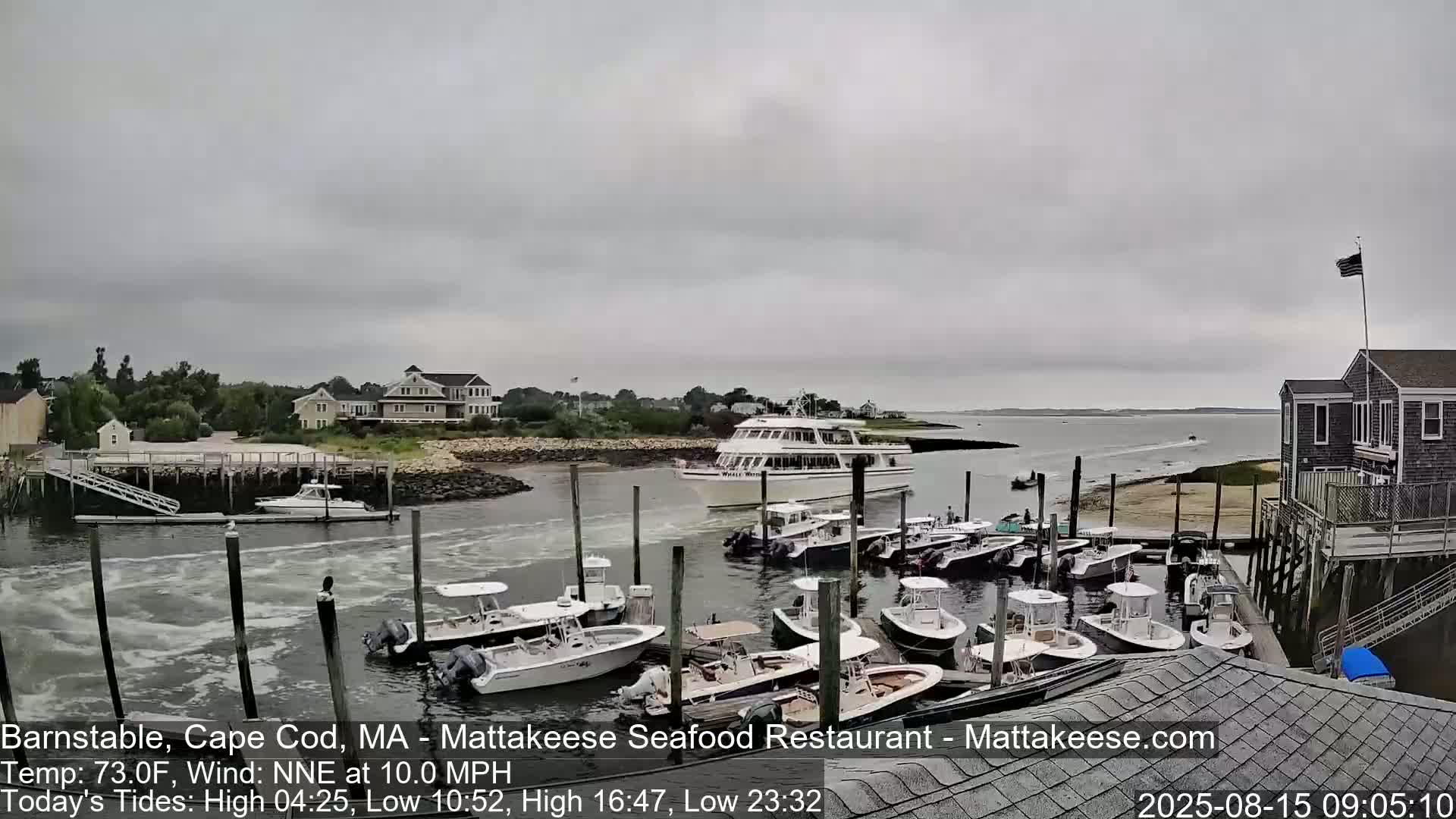 A partly cloudy day shows many small motorboats docked at a waterfront location with a building and calm water.