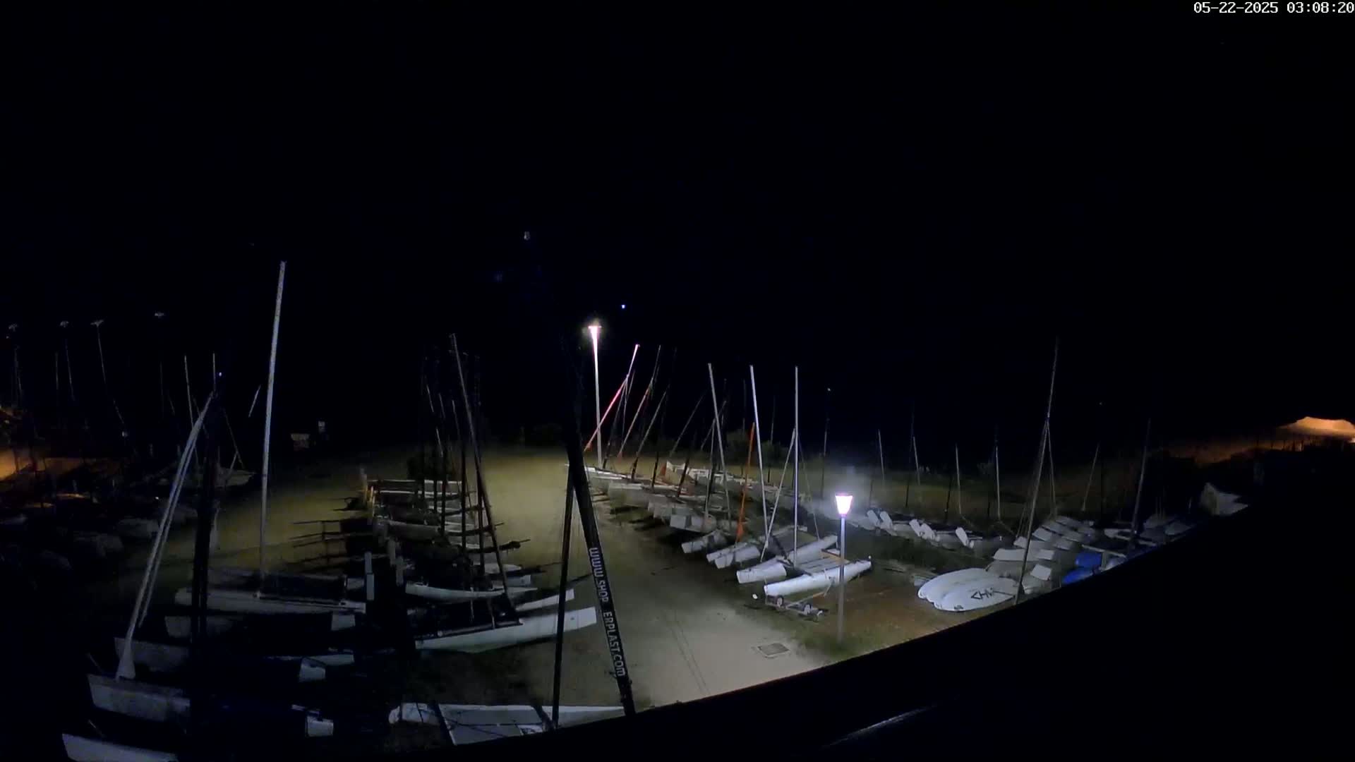 Many sailboats are docked at night under a dark sky.