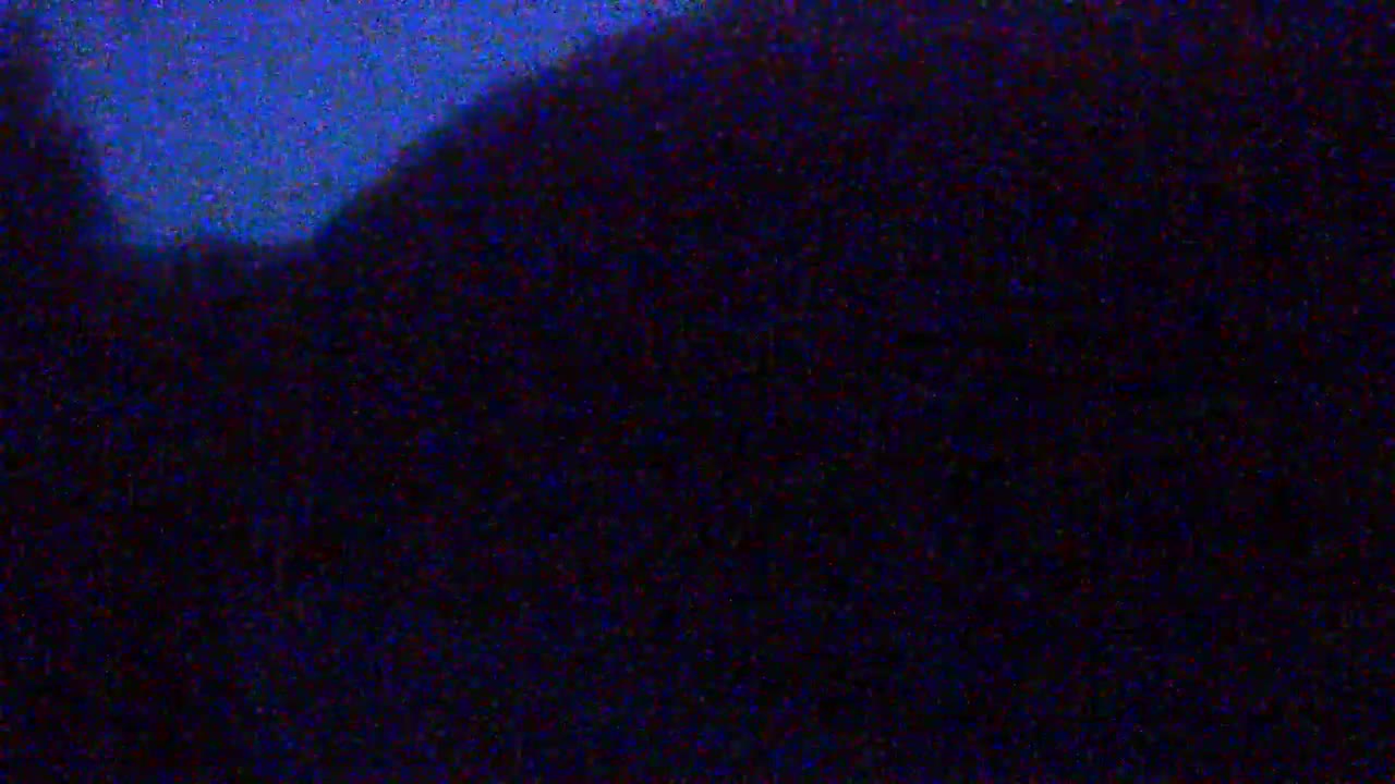 A dark, blurry image shows a mostly black area with a hint of blue in the upper left corner suggesting nighttime conditions.