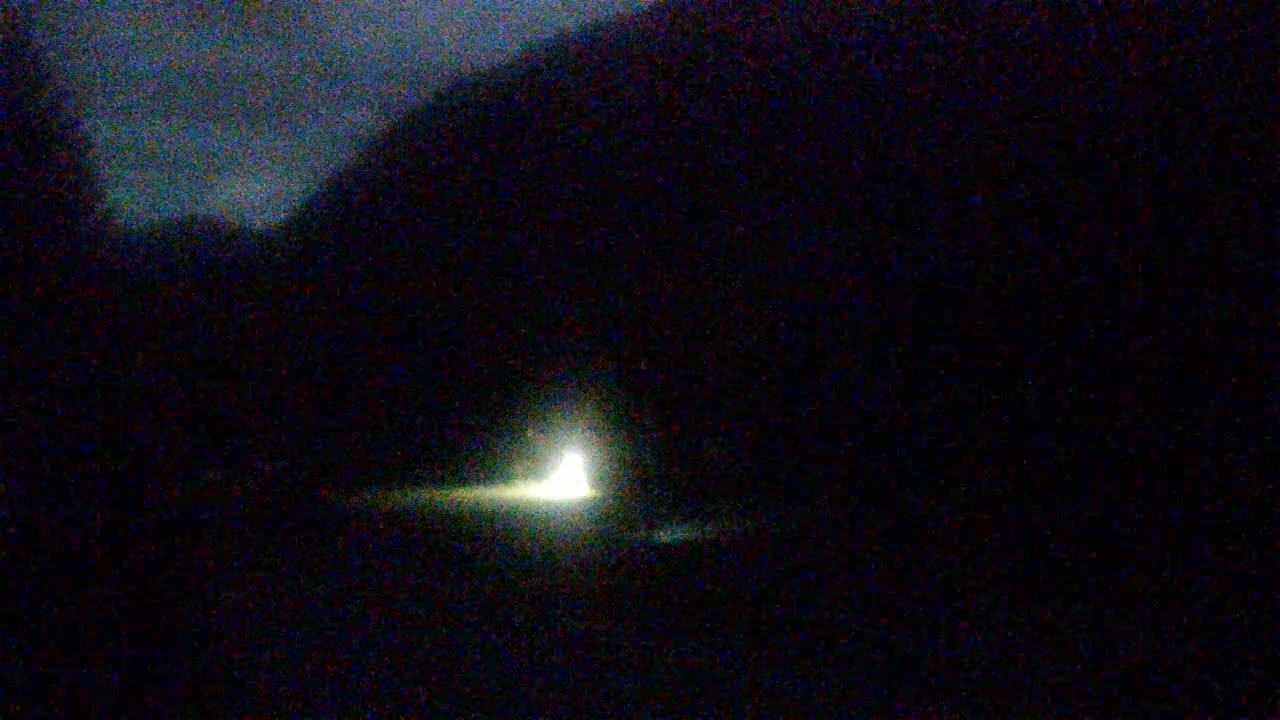 A bright light is visible at the end of a dark road at night.