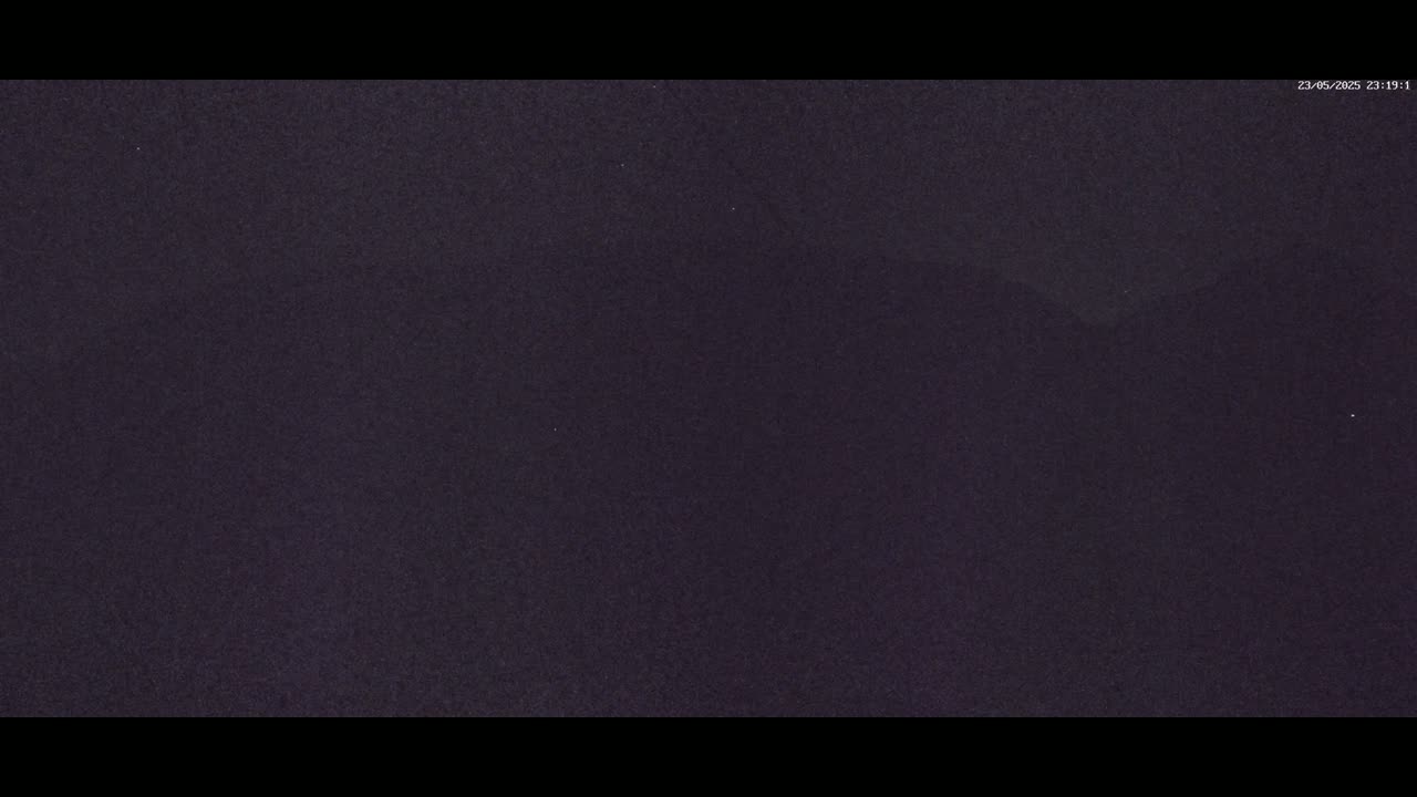A dark, nighttime image shows a mostly featureless, dark purplish-grey sky.