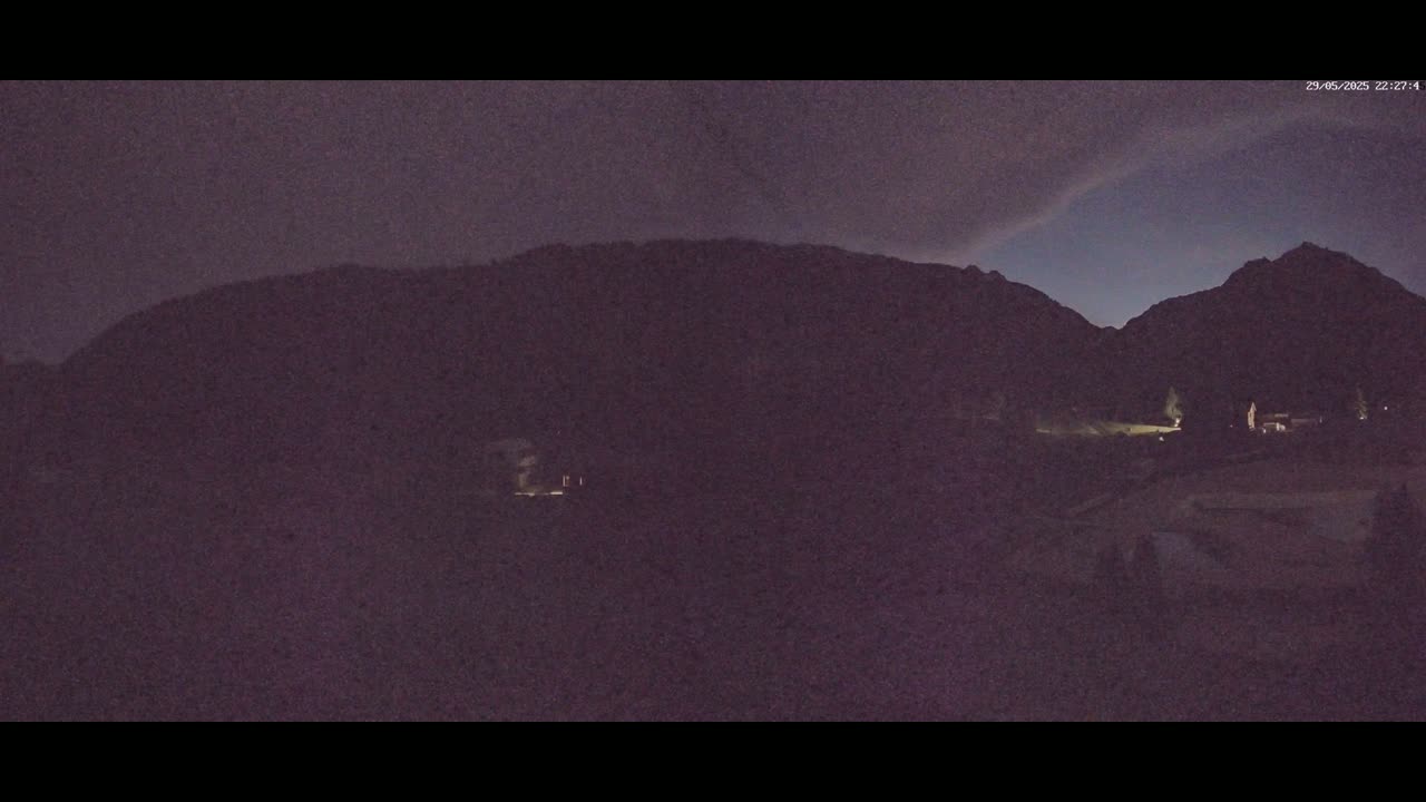 A nighttime view of dark mountains under a dusky, purplish sky.