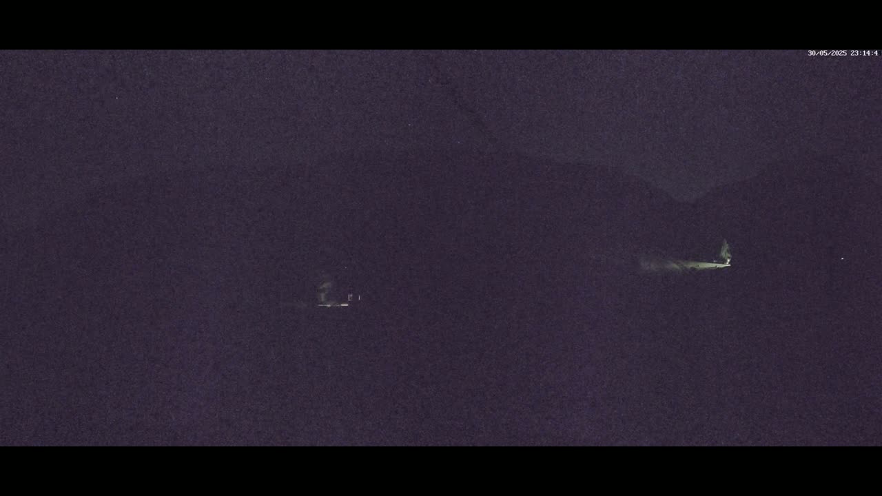 Two dimly lit structures are visible in the dark, possibly at night.