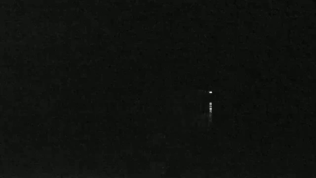 A dimly lit, tall structure is visible in the distance at night, reflecting slightly on dark water.