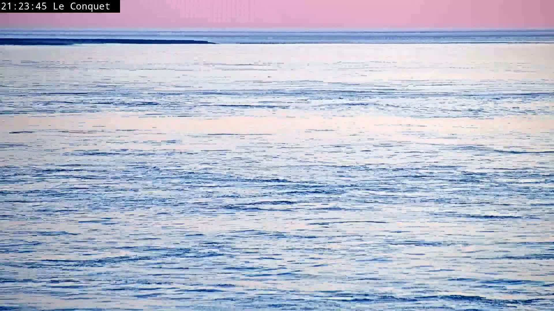 A calm body of water with a pinkish sky at dusk.