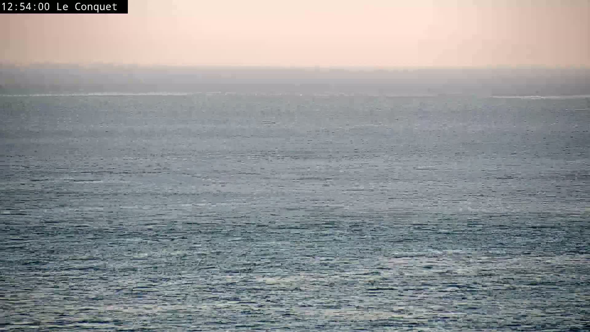 A hazy, calm ocean stretches to a pale horizon under a light, overcast sky.