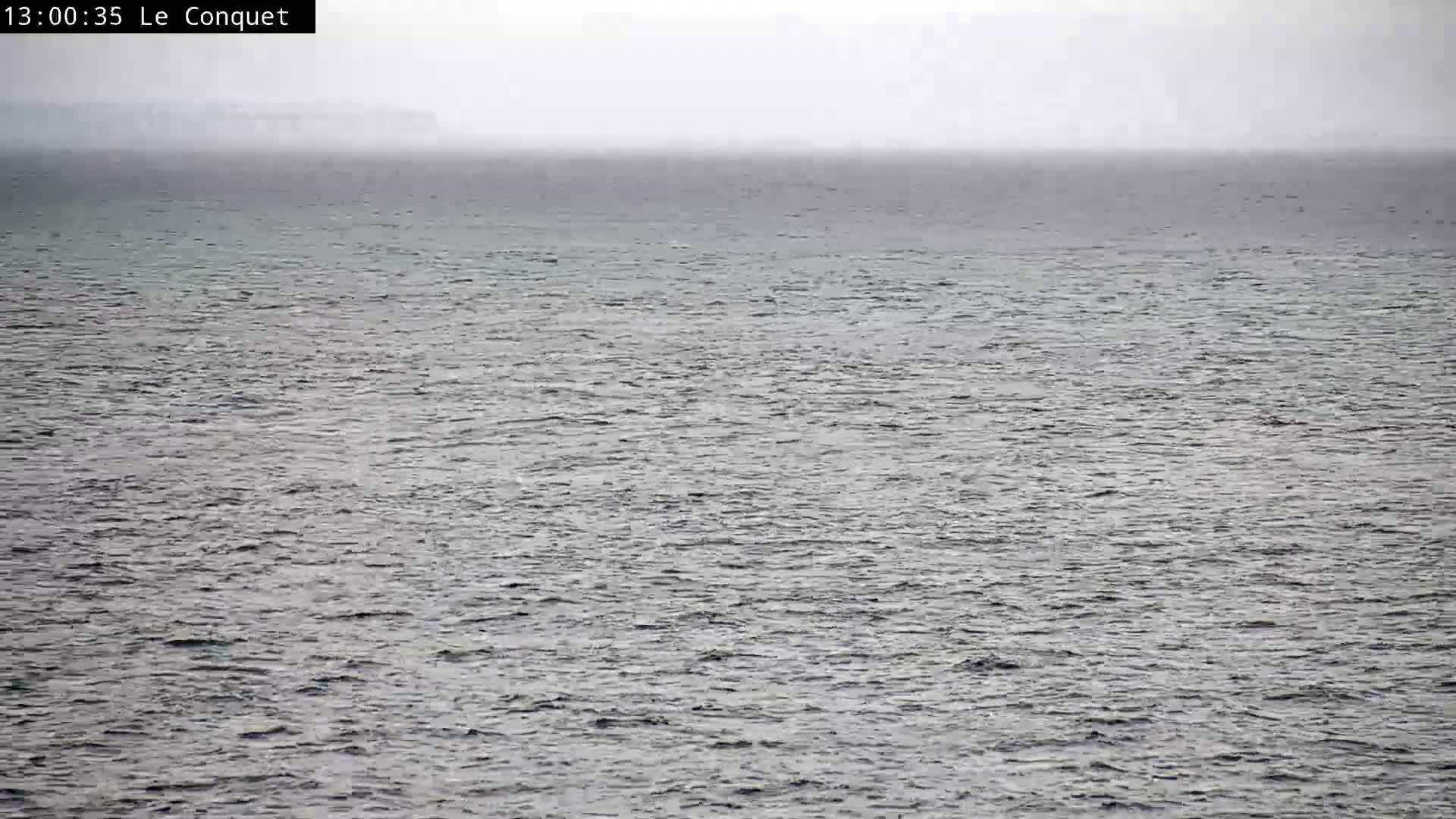 A hazy, gray day shows a mostly calm expanse of dark gray water.