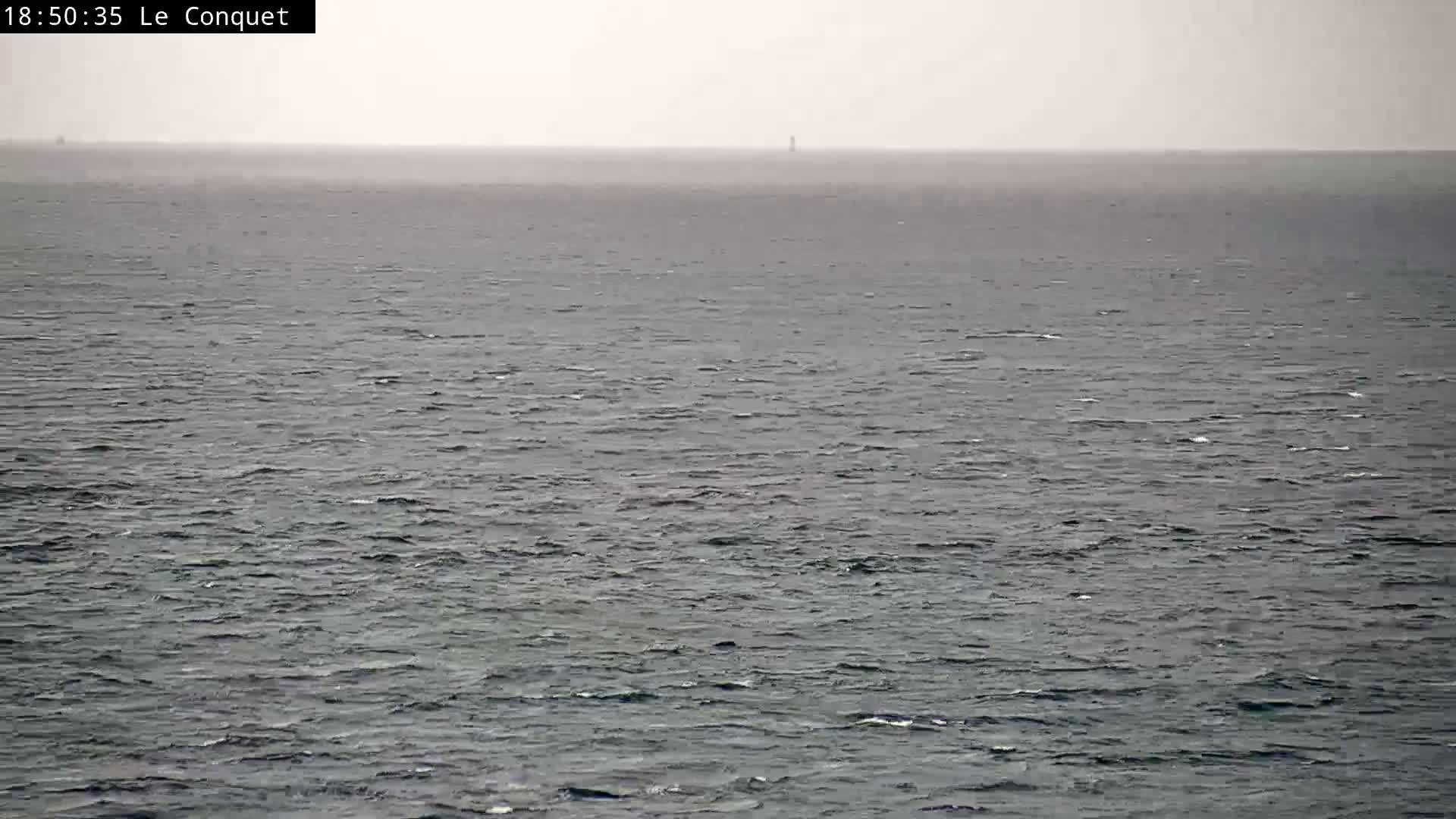 A distant, hazy view of a choppy sea under an overcast sky.