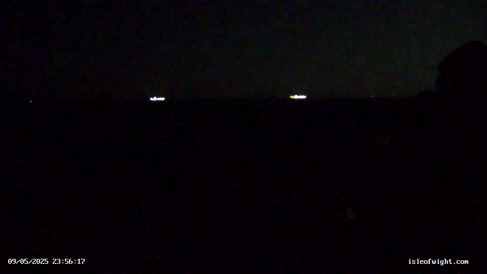 Two distant lights are visible on a dark, nighttime horizon.