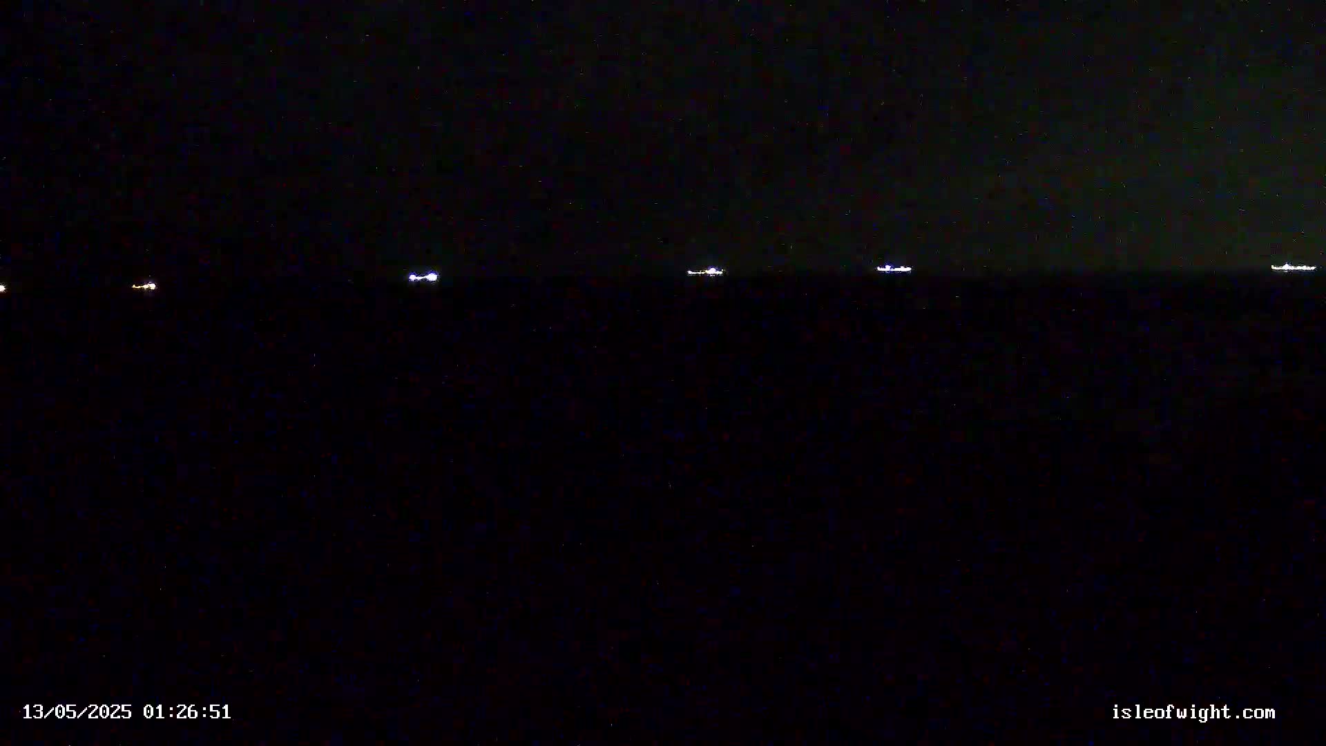 Several small lights are visible on a dark body of water at night under a starry sky.