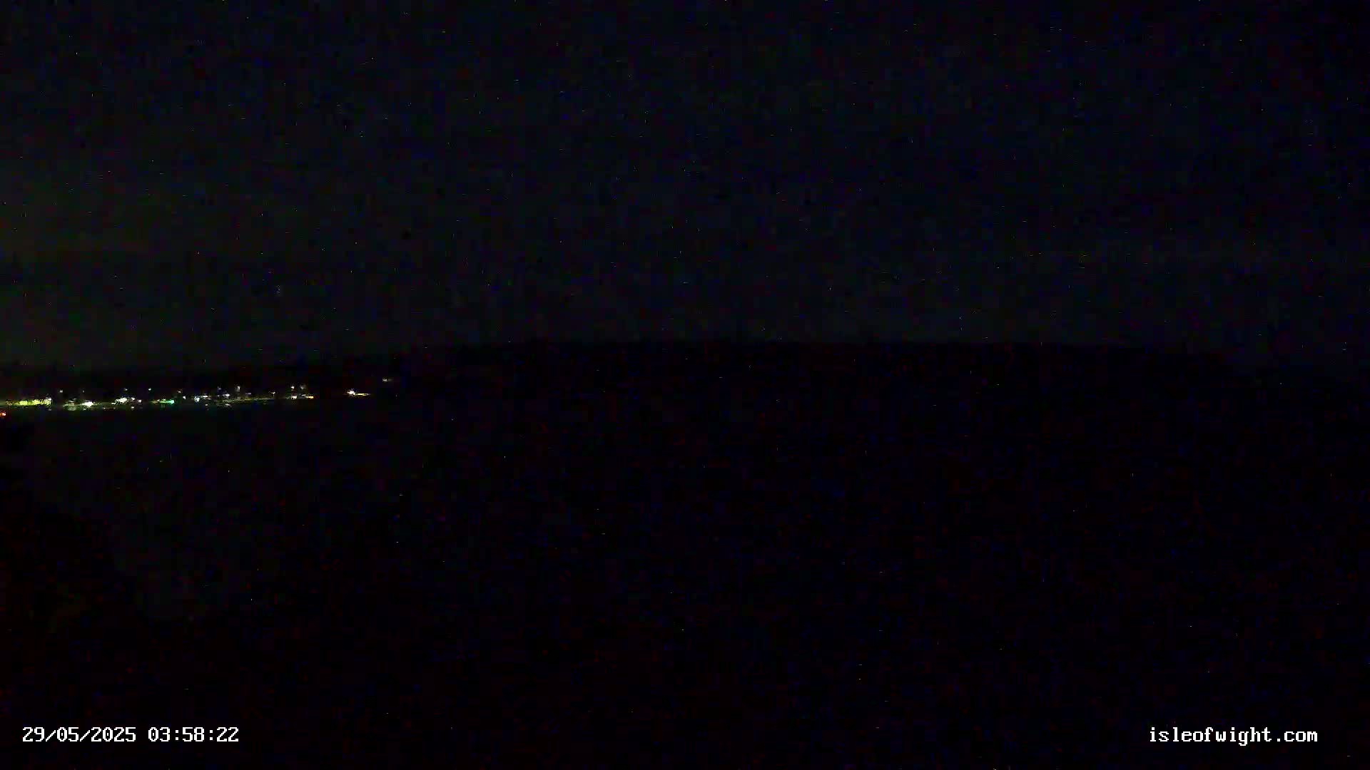 A dark, nighttime view shows a distant line of lights below a starlit sky.
