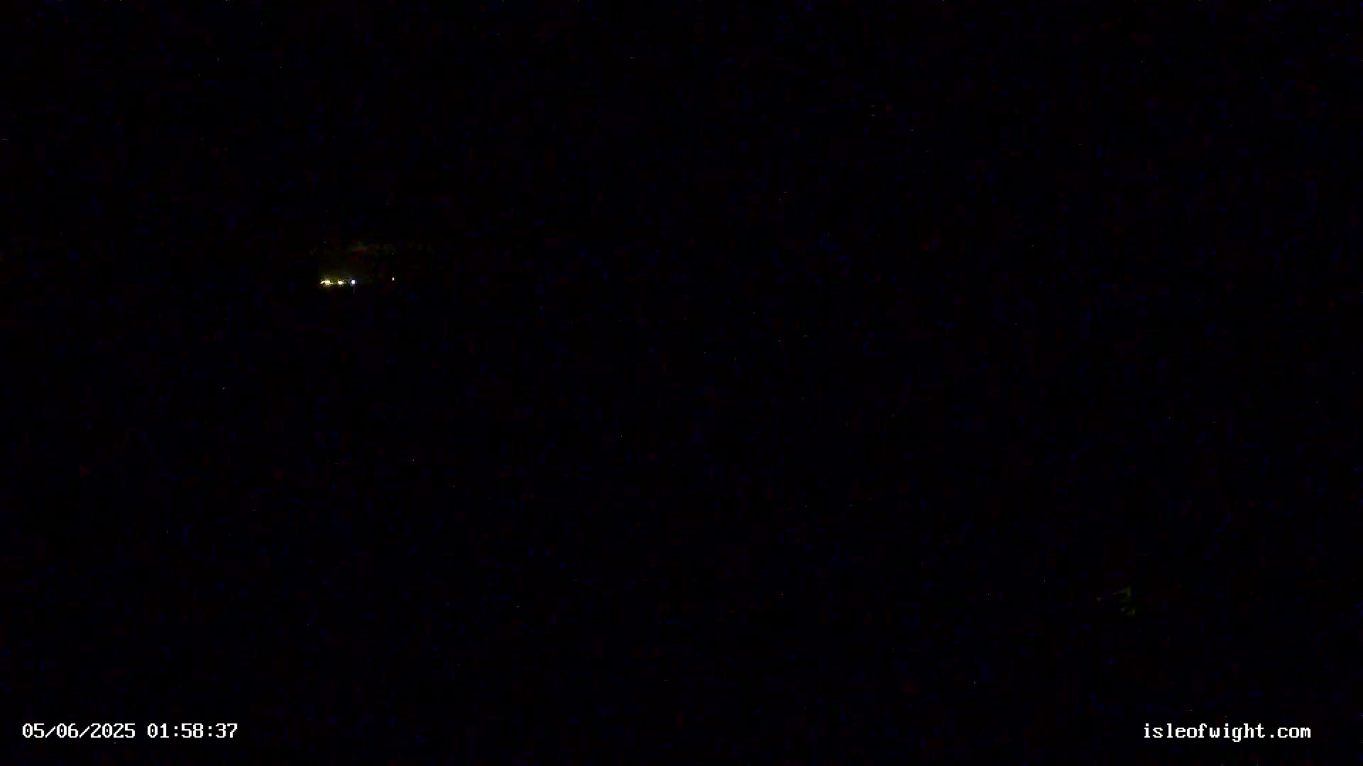 A dark, nighttime scene shows a few distant lights in the center.
