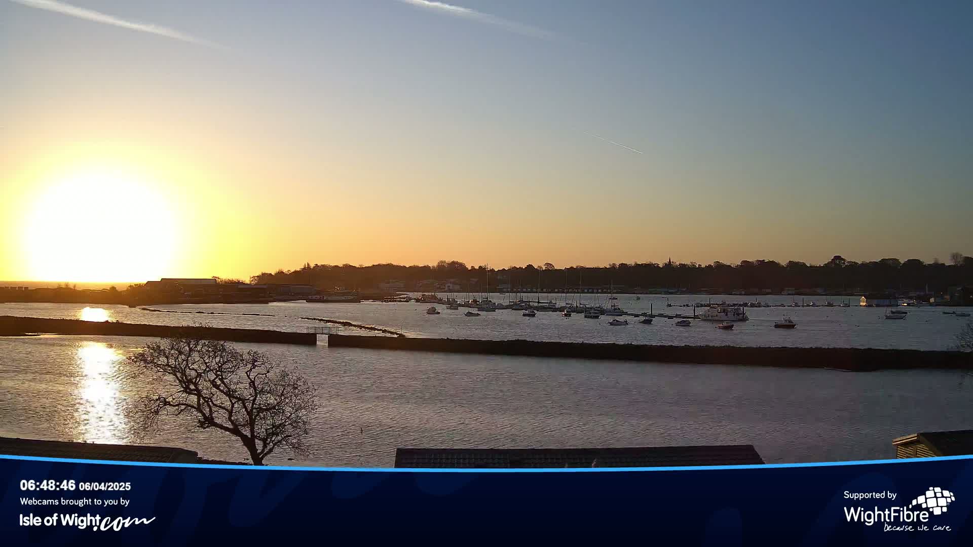 A calm body of water with numerous boats at sunset, under a clear sky.