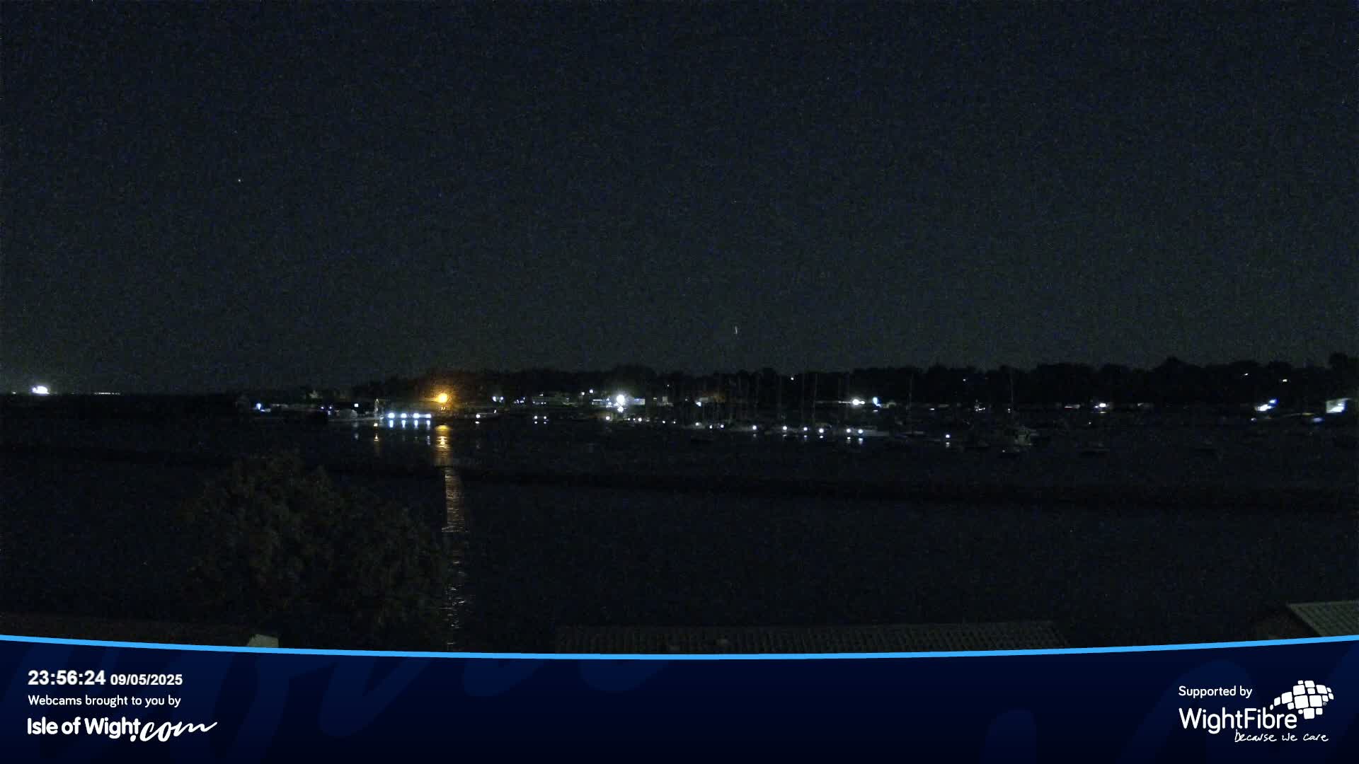 A nighttime view of a harbor filled with boats under a clear, dark sky.