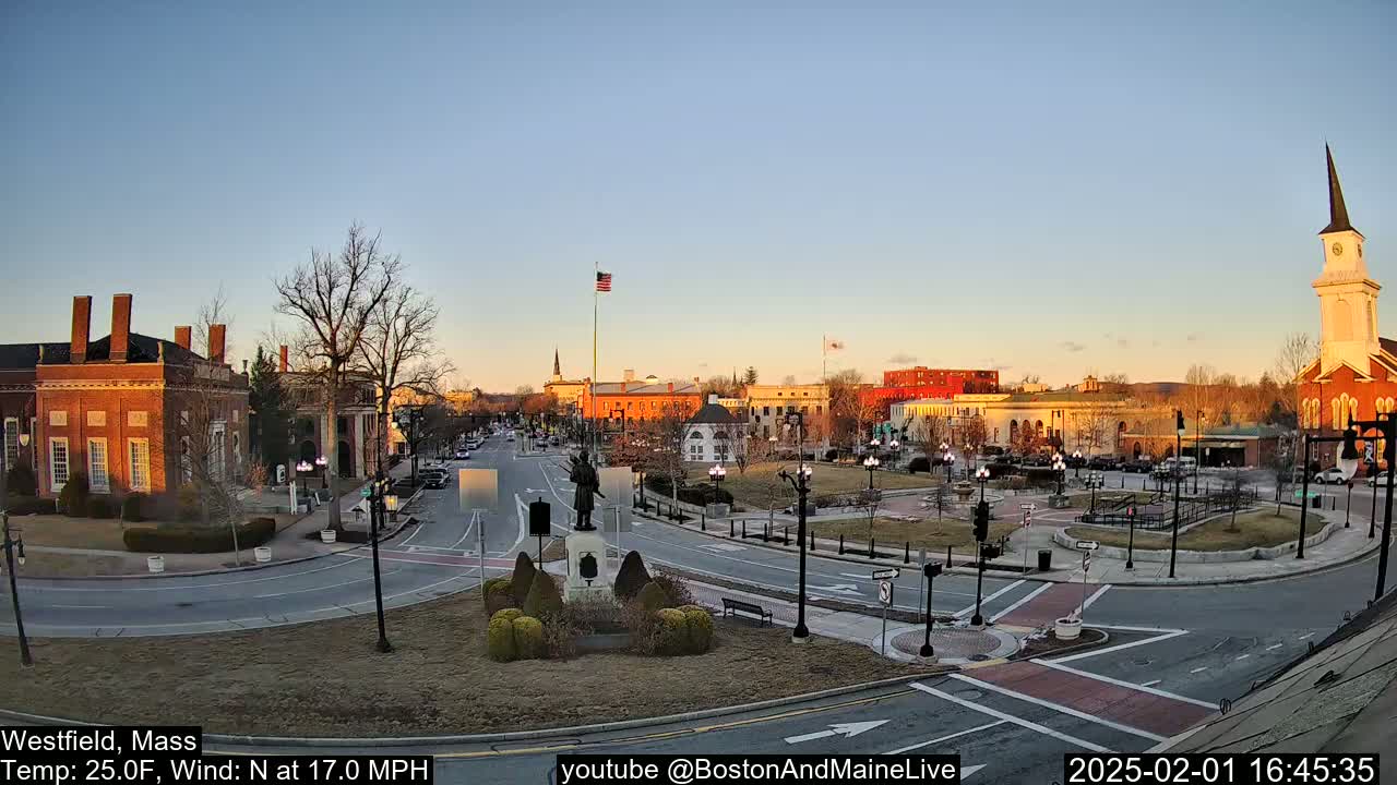 A town square with brick buildings, a statue, and a church steeple is visible under a clear, twilight sky.