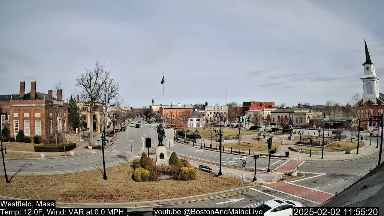 A town square with brick buildings, a monument, and a church steeple is visible under a mostly clear sky.