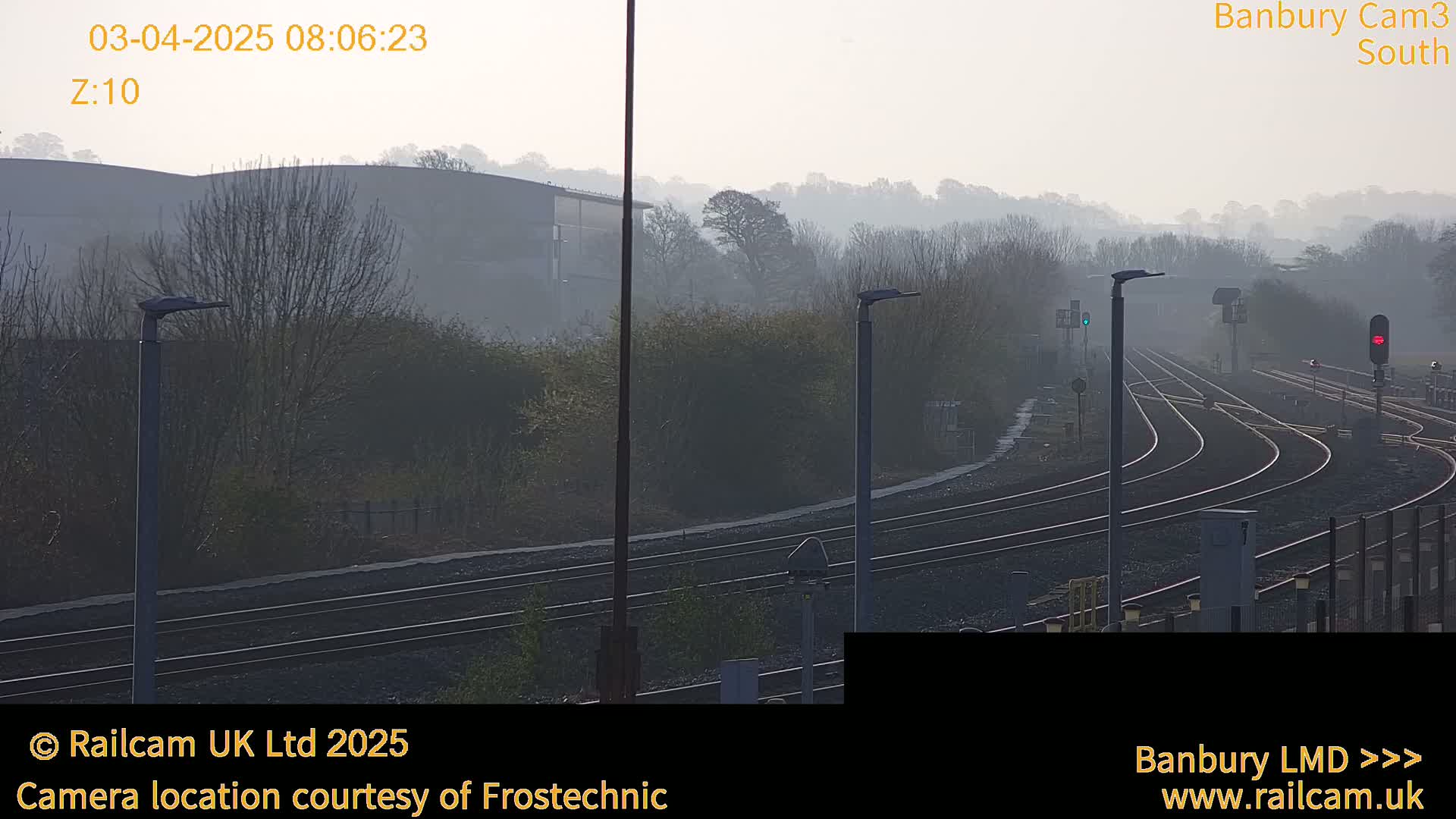 A foggy view of a railway yard with multiple train tracks curving into the distance, under a hazy sky.