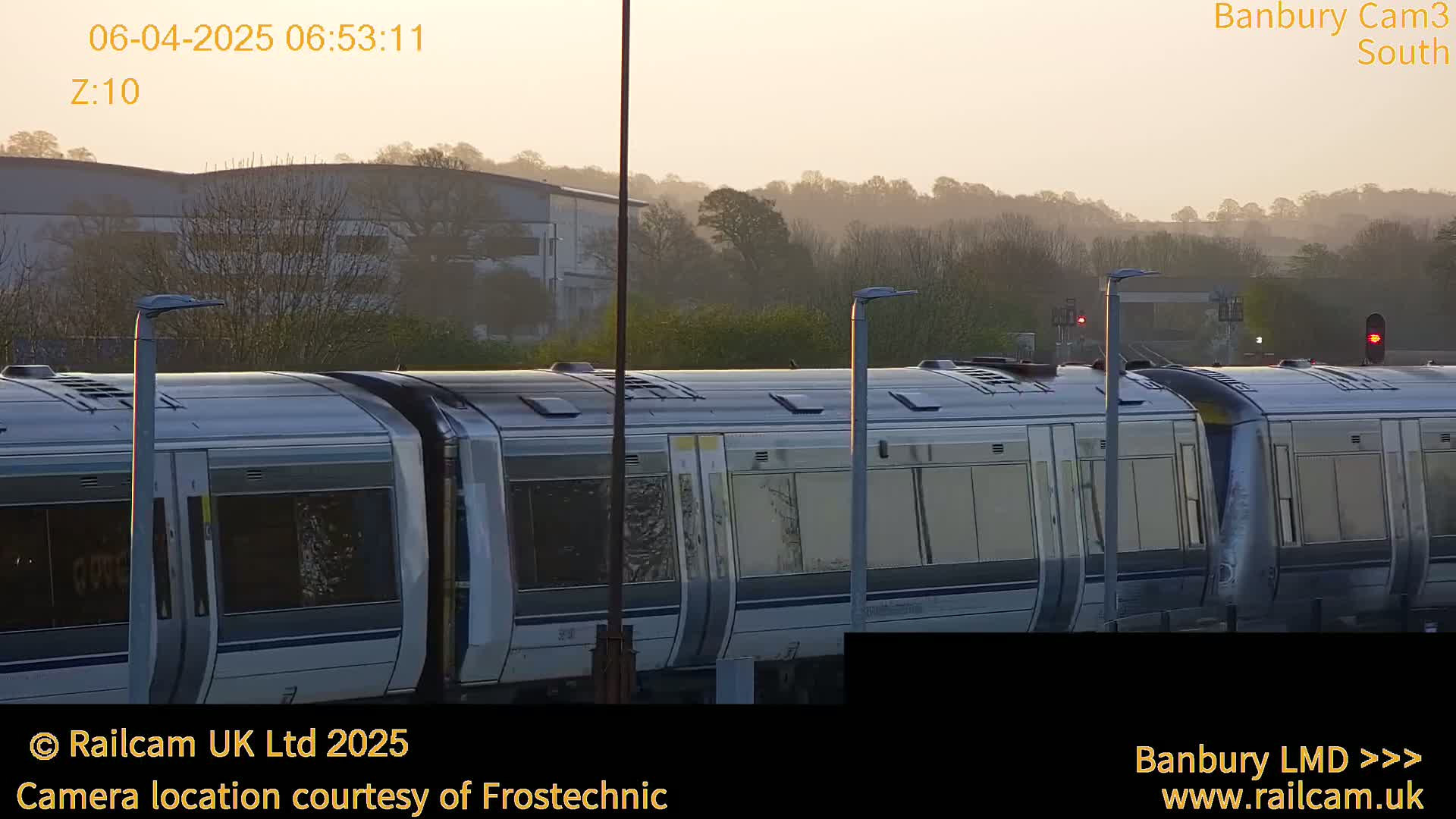 A long train is seen at a station on a hazy morning.