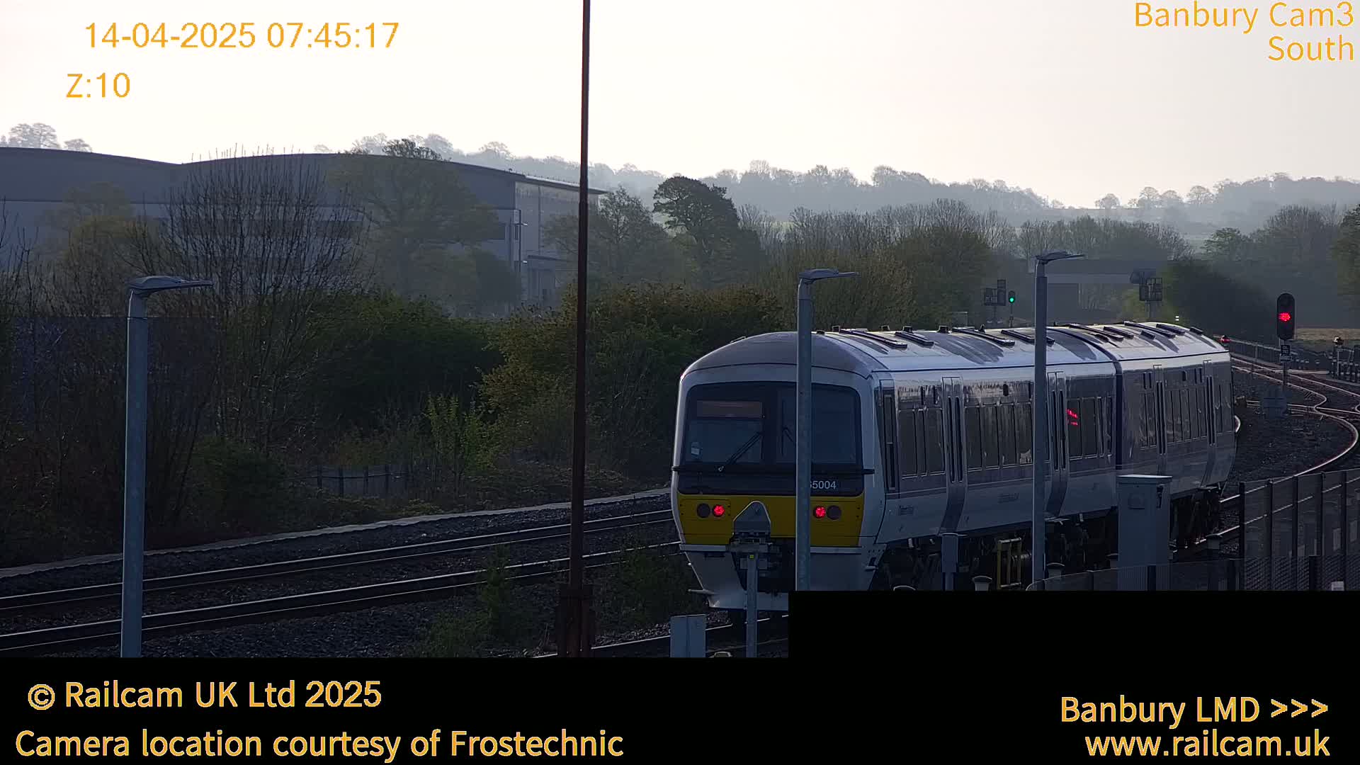 A train approaches a station on a slightly hazy morning.