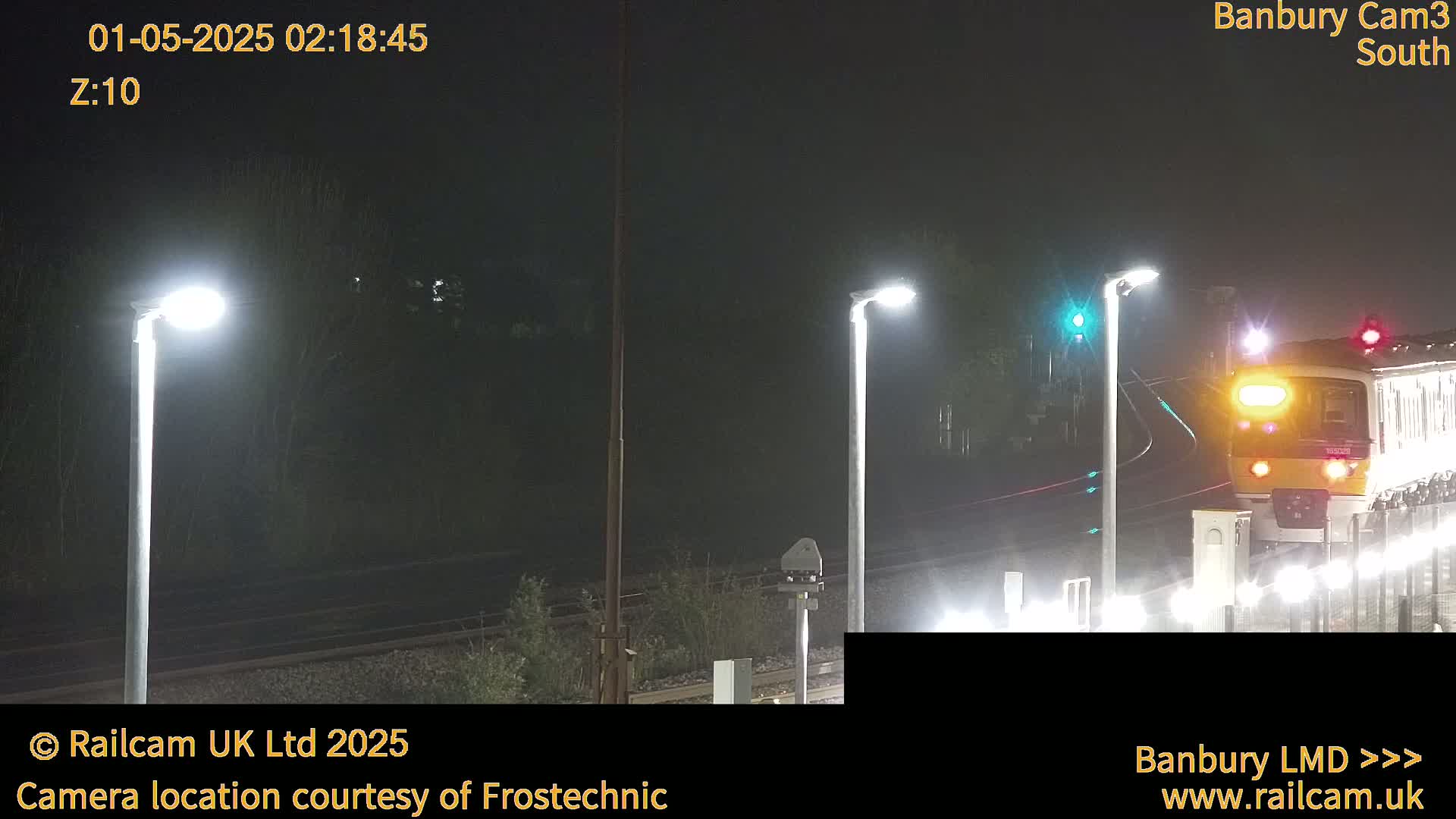 A train passes through a dimly lit station at night in foggy conditions.