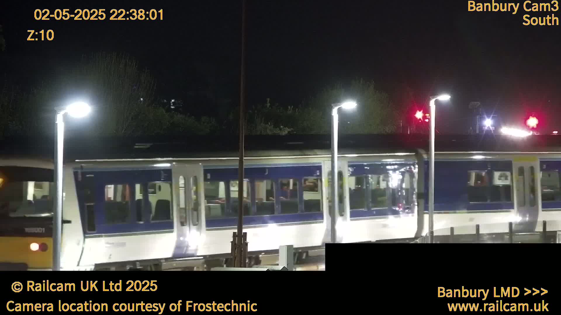 At night, a passenger train passes by under bright lights.