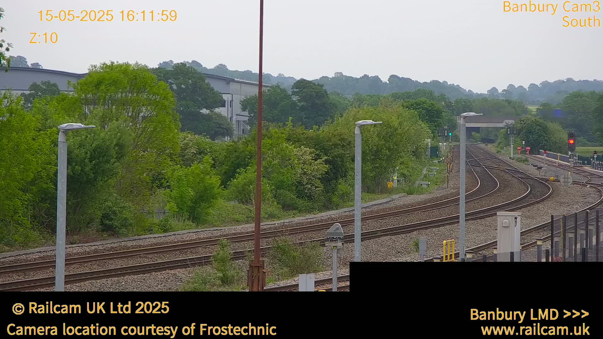 A view of several train tracks curving through a lush green landscape under an overcast sky.