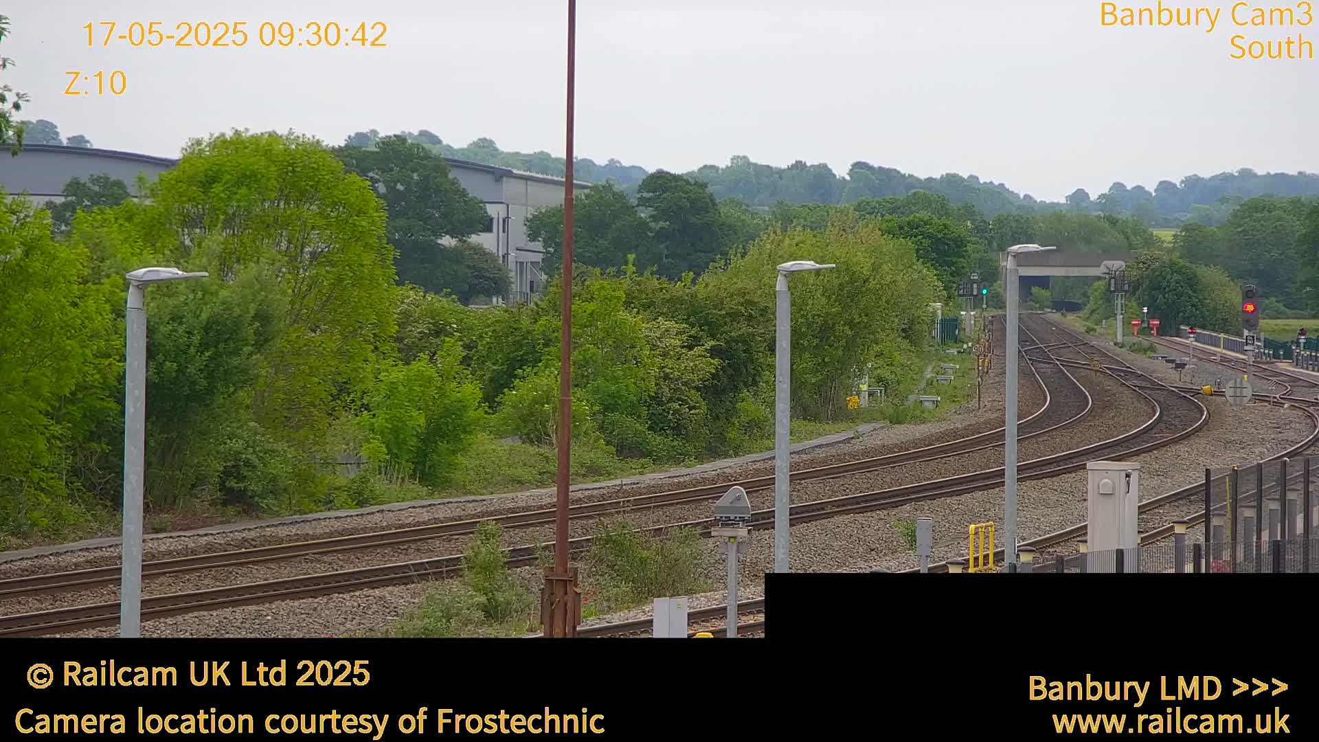 A view of several curving train tracks in a lush green landscape under an overcast sky.