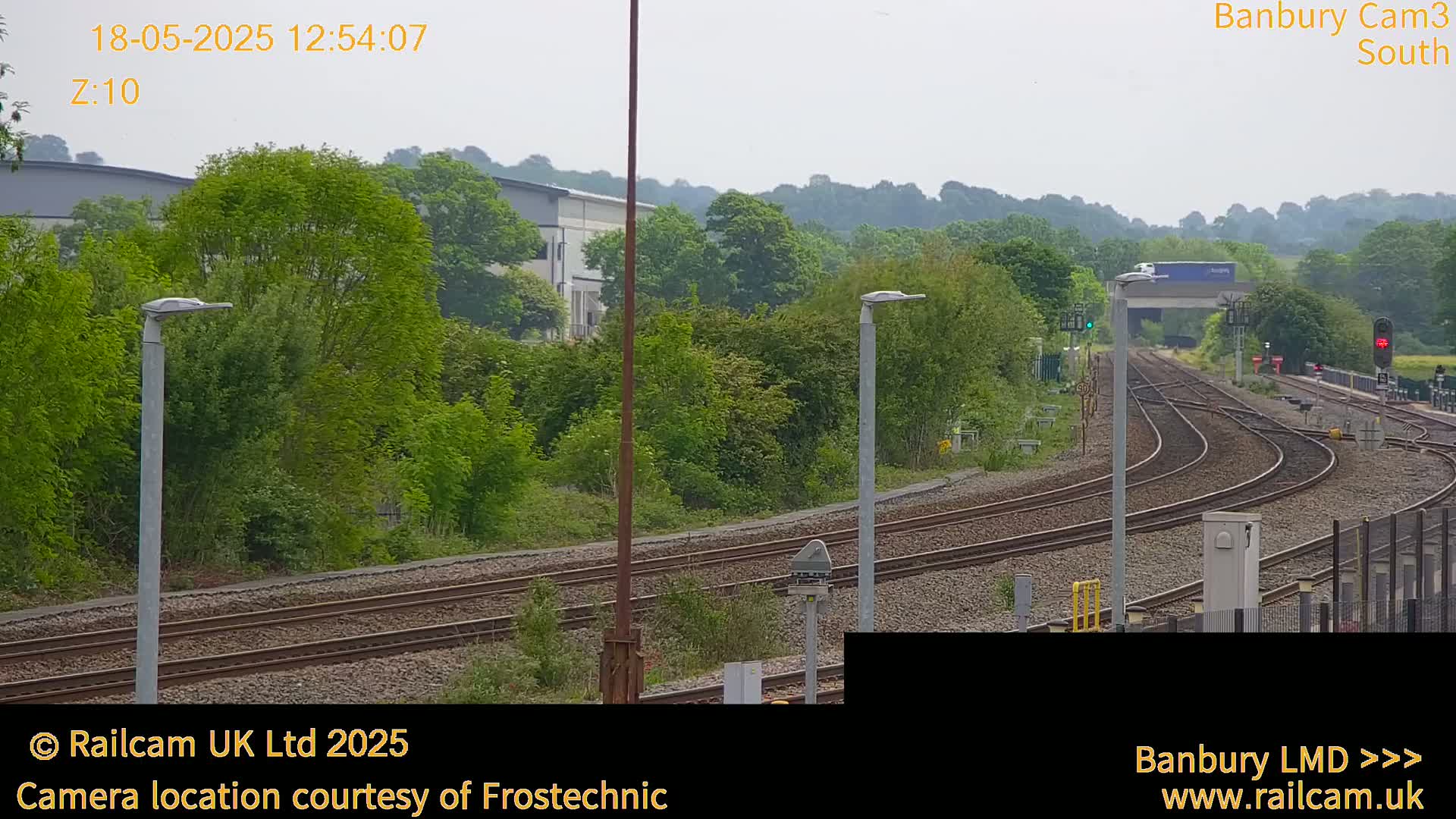 A long shot of train tracks curving through a green landscape under an overcast sky.