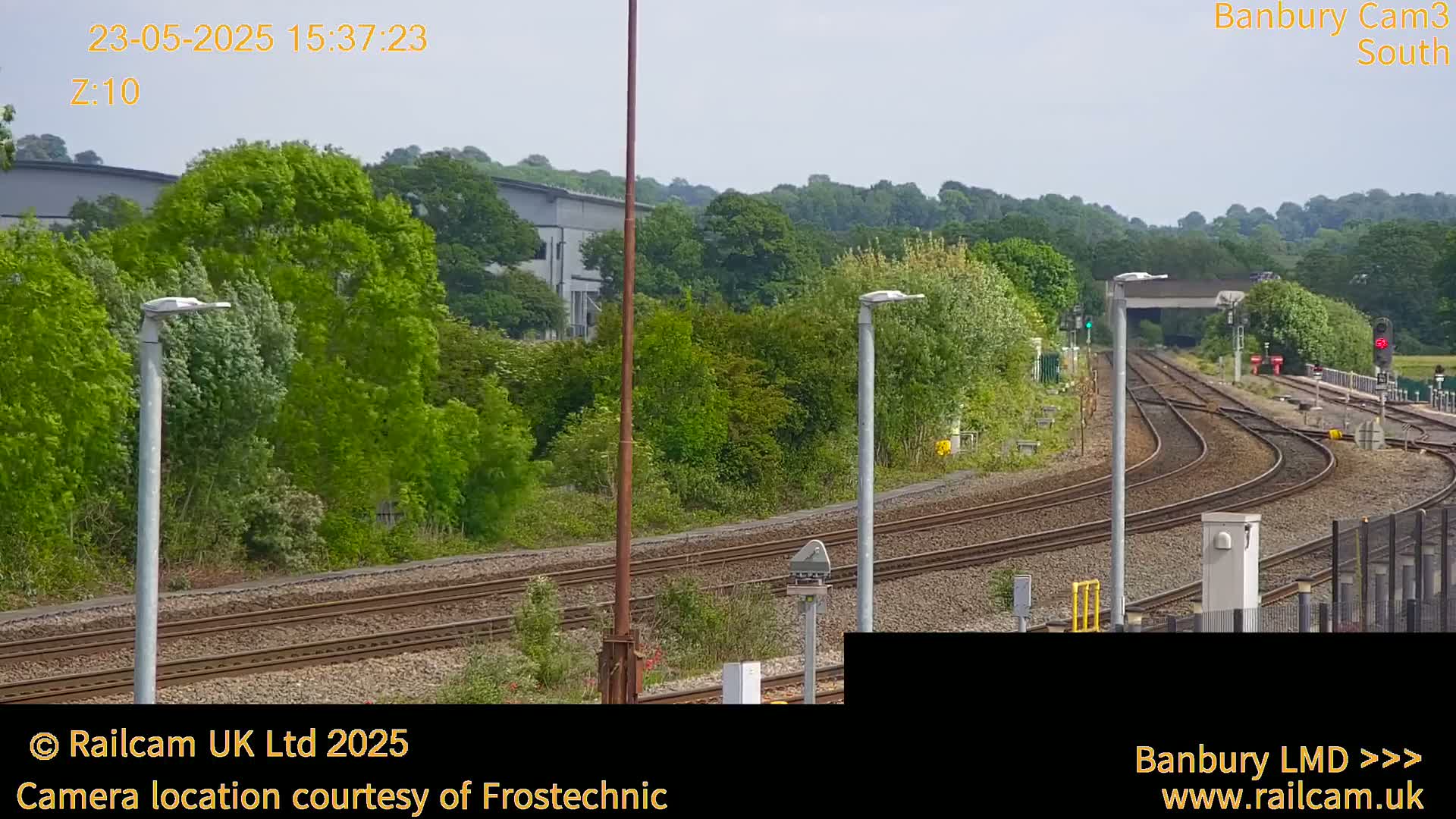 A view of several train tracks curving through a green landscape under a partly cloudy sky.