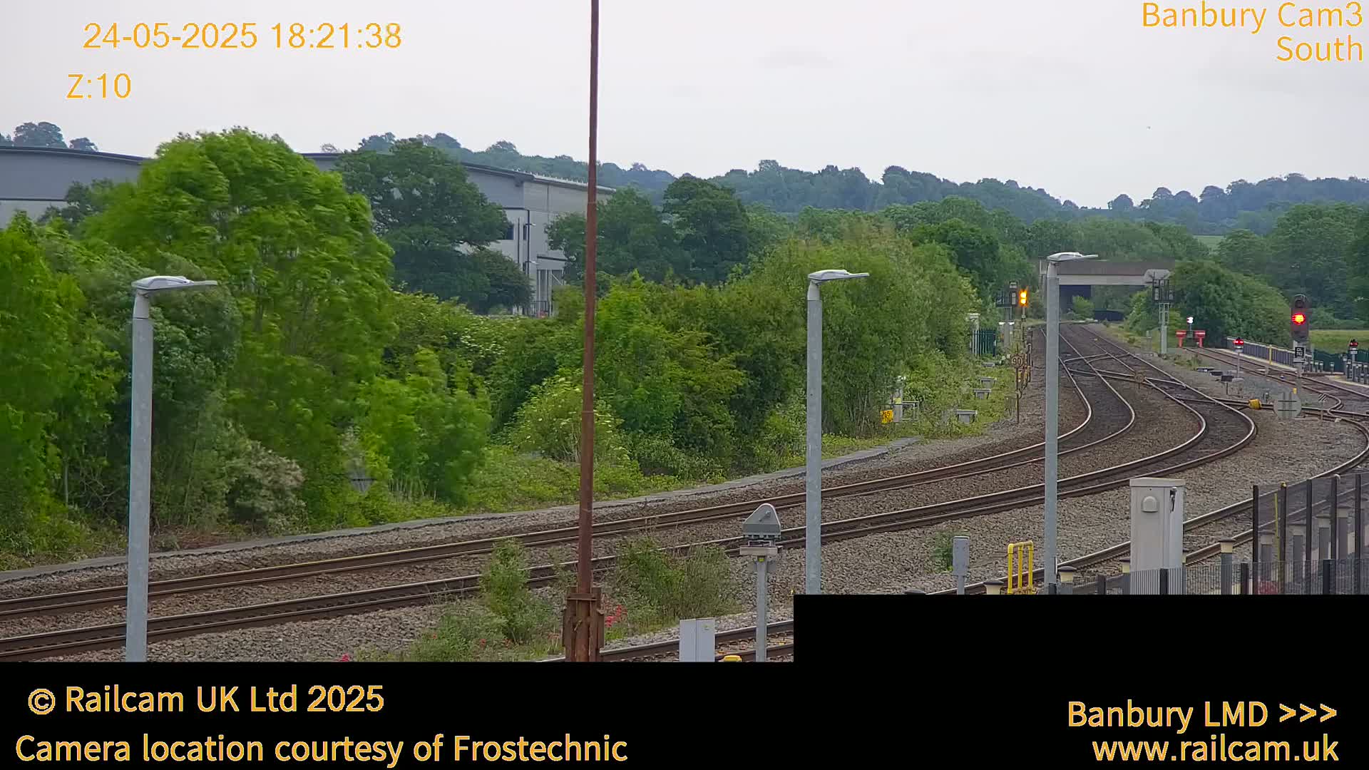 A view of a railway track curving through lush green vegetation under an overcast sky.