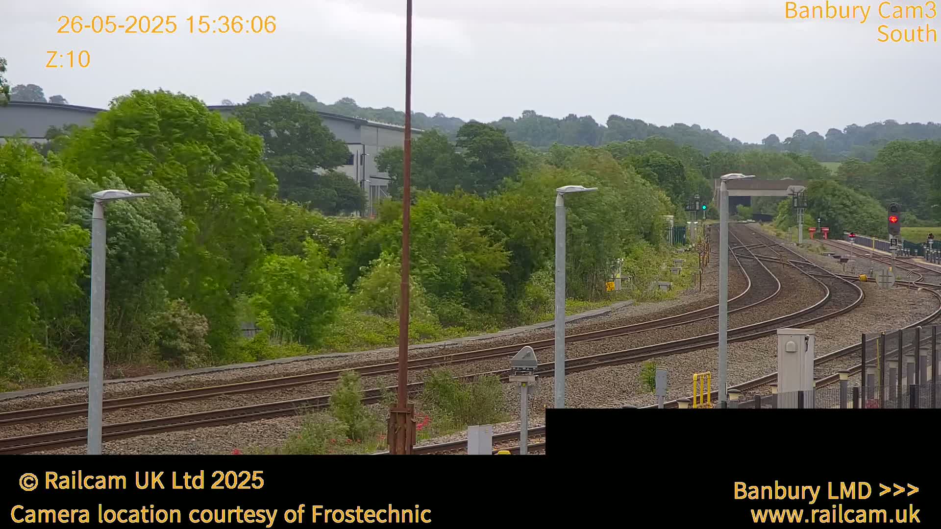 A view of several train tracks curving through a lush green landscape under an overcast sky.
