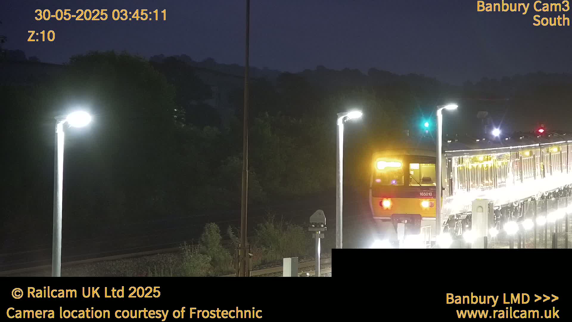A train passes at night under illuminated streetlights.