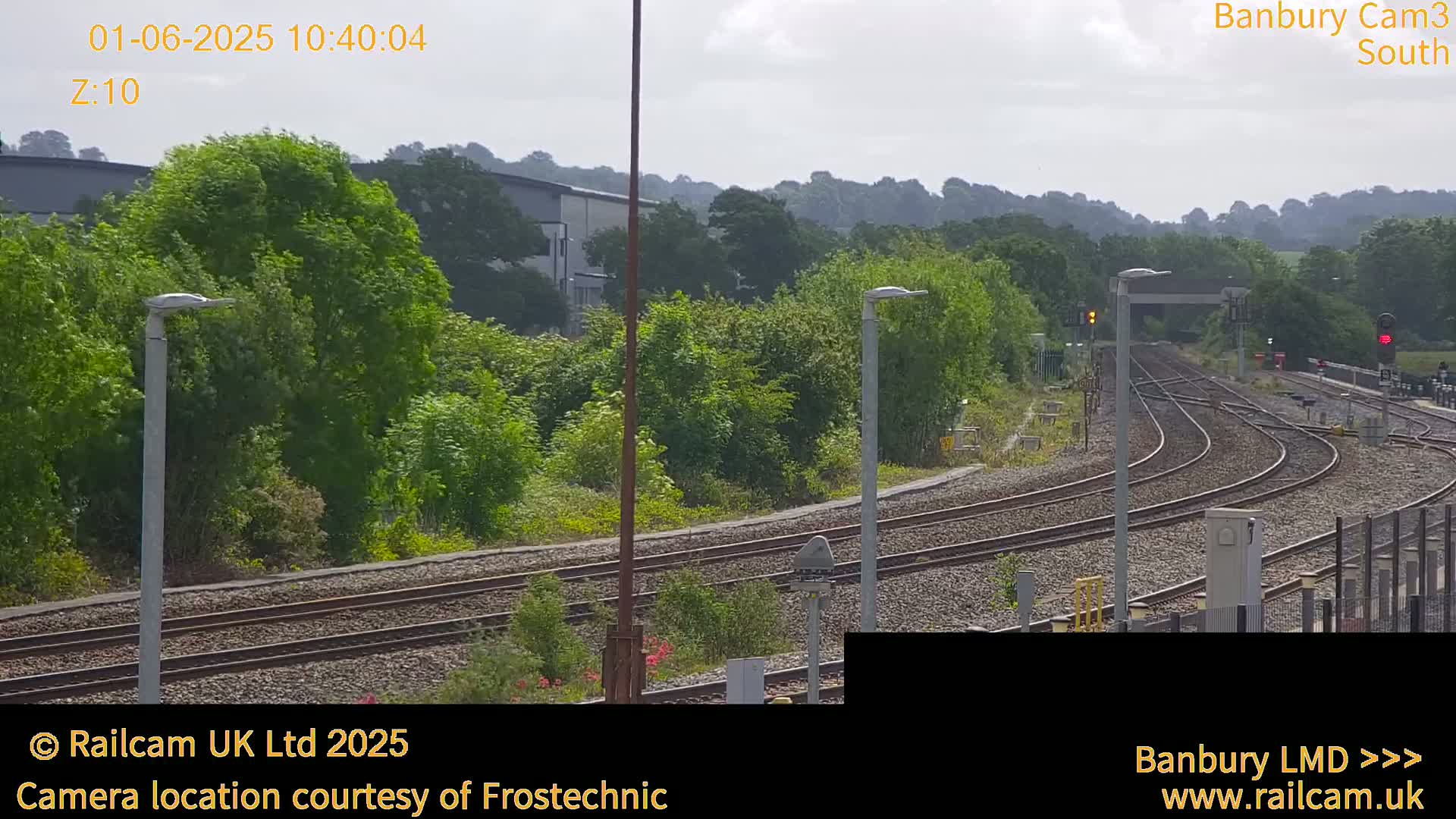 A slightly overcast view of a railway track curving through a landscape of green trees and shrubs.