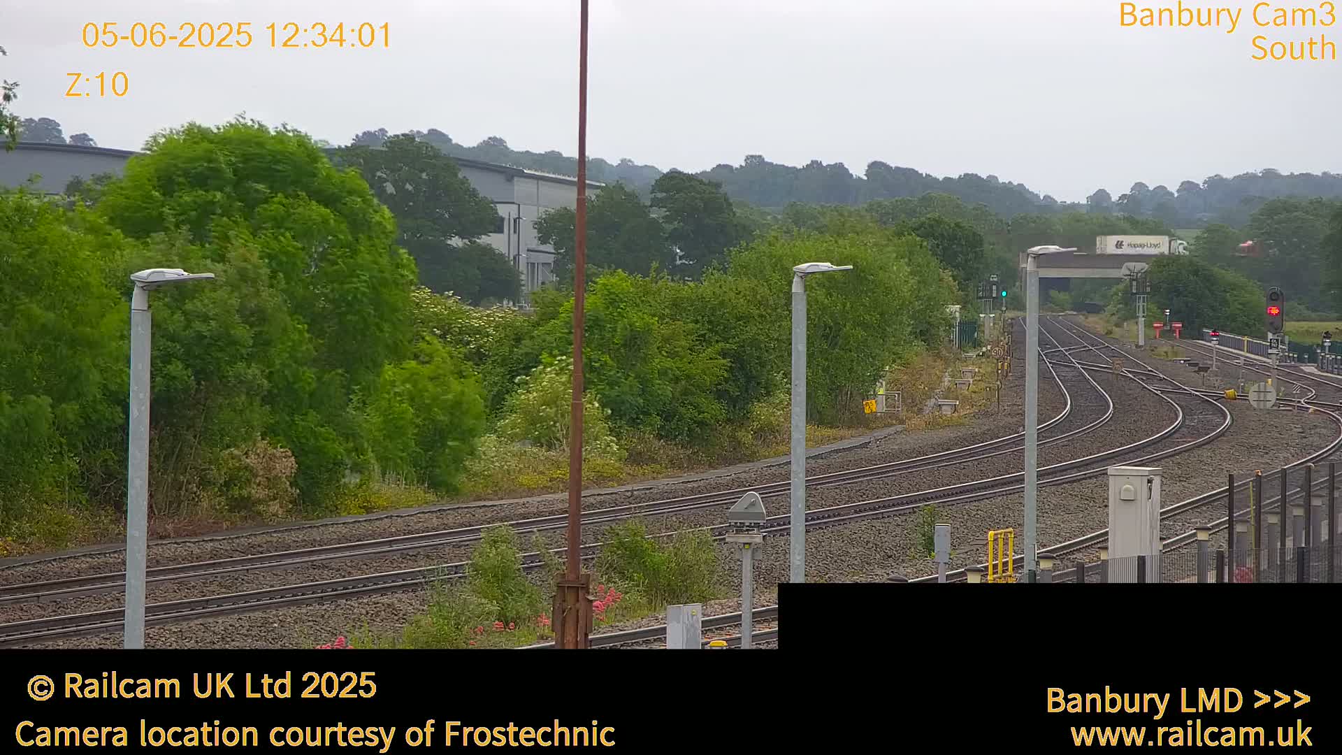 A view of train tracks curving through a green landscape under an overcast sky.