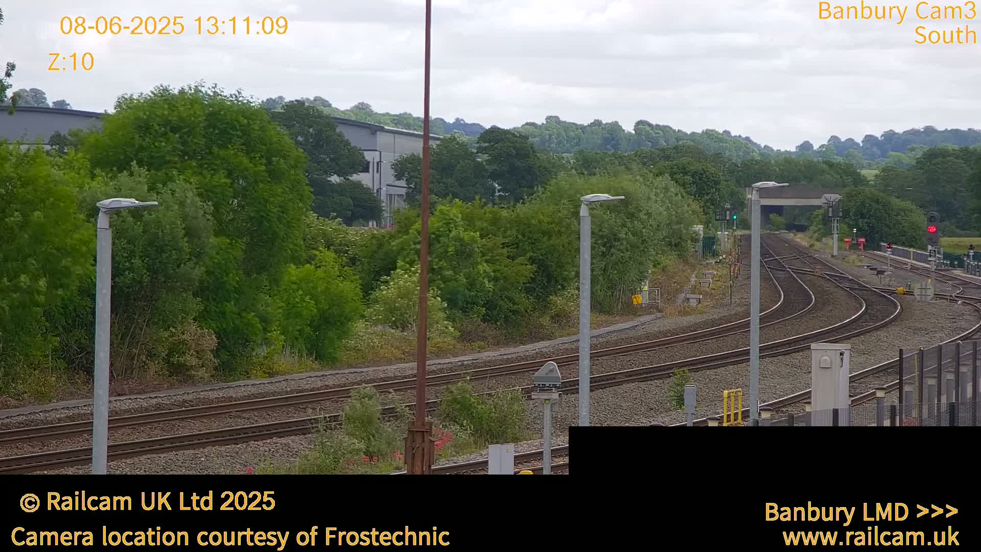 A view of a railway track curving through a lush green landscape under an overcast sky.