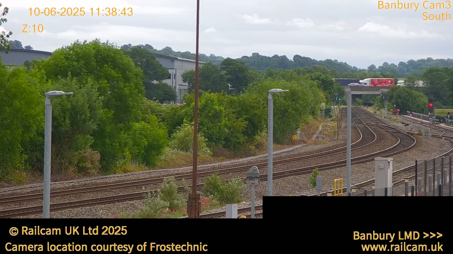 A slightly overcast view of a train yard with multiple sets of tracks curving through lush green vegetation.