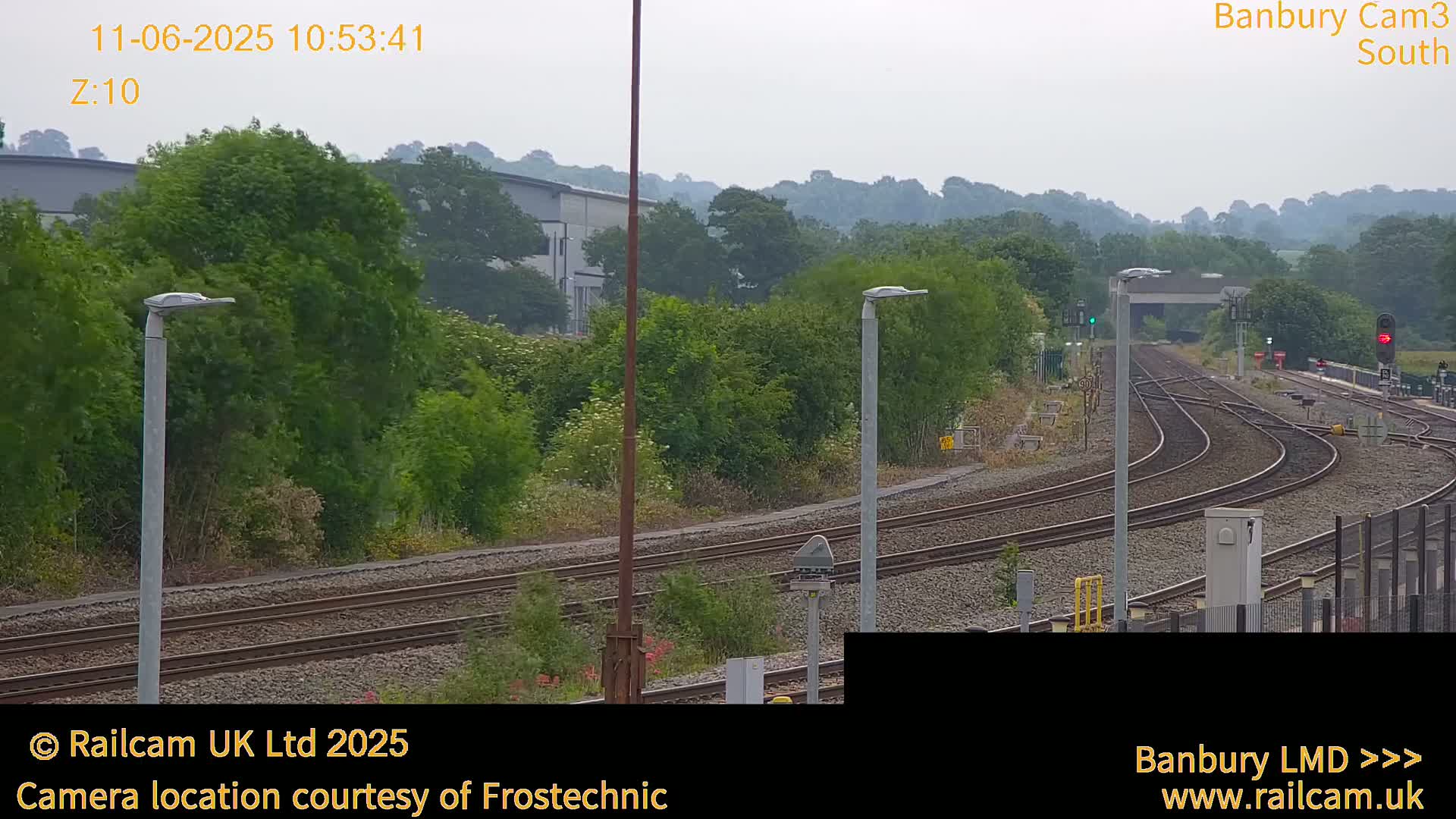 A view of several train tracks curving through a lush green landscape under an overcast sky.