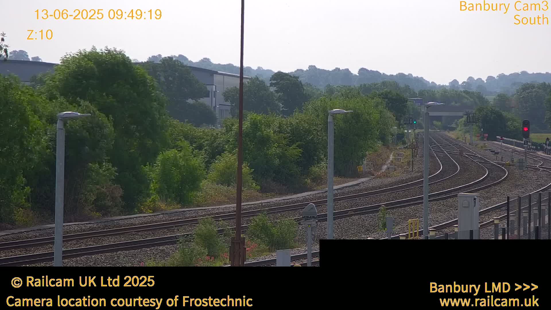 A view of train tracks curving through a lush green landscape under a hazy sky.