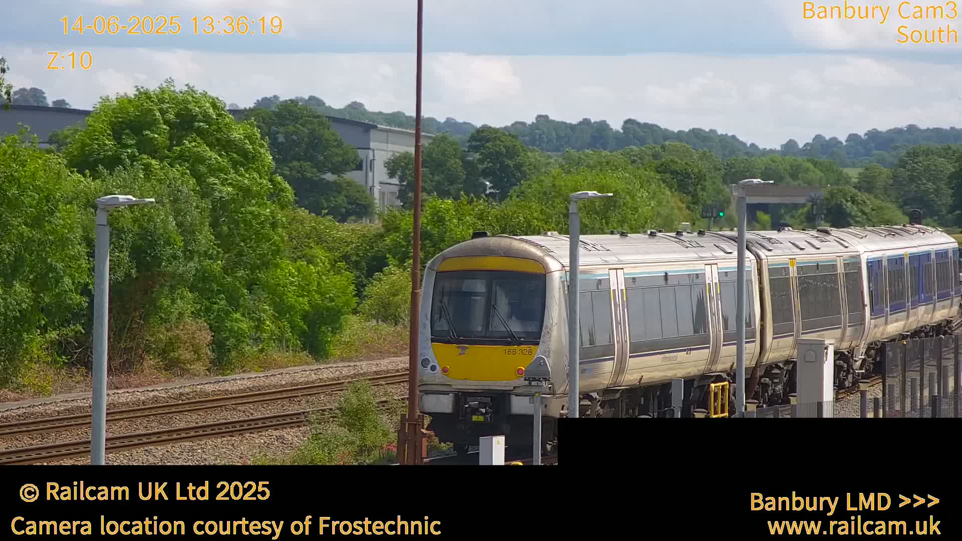 A multi-car passenger train approaches the camera on a sunny day.