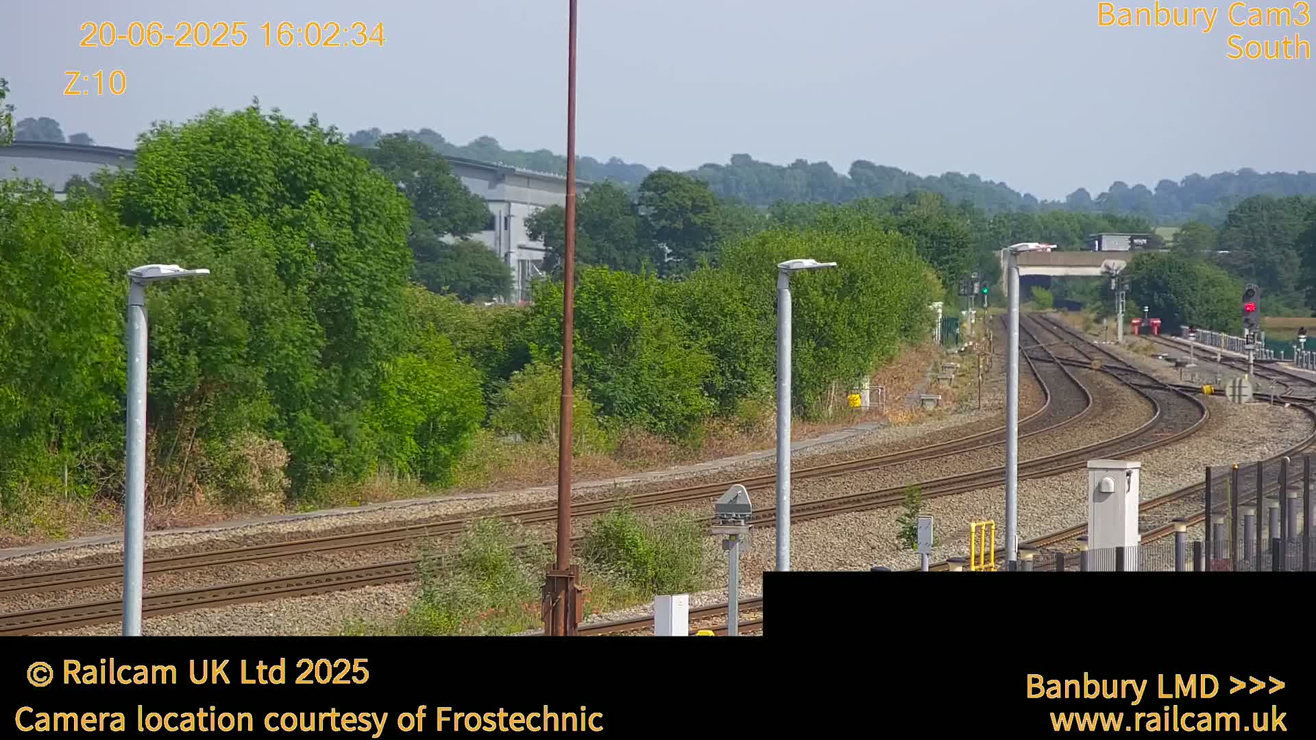 A view of train tracks curving through a green landscape under a bright, sunny sky.