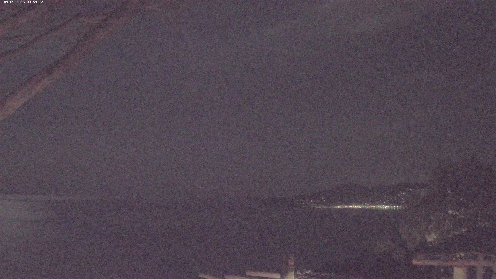 A nighttime, long shot of a body of water with distant city lights on the far shore under a dark, overcast sky.