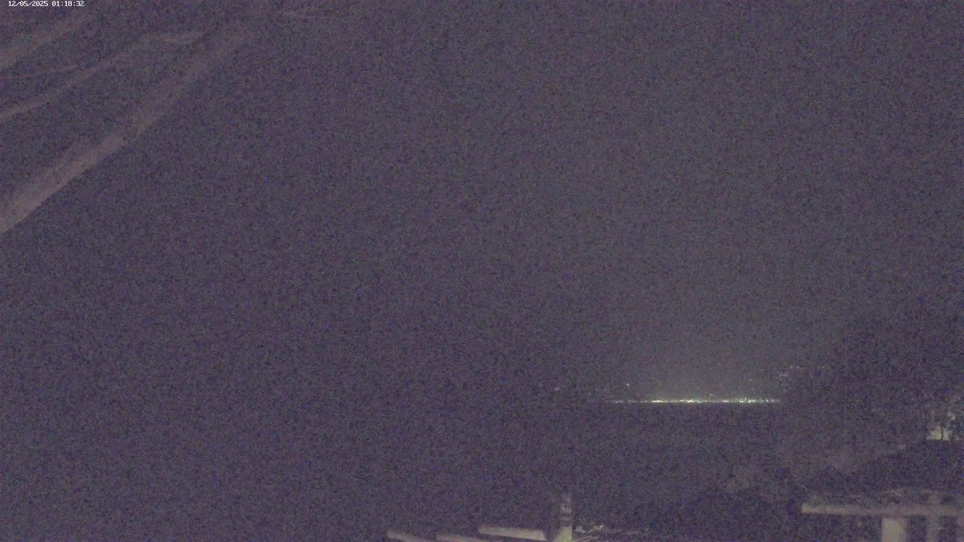 A dark, nighttime scene shows a distant line of lights on the horizon.